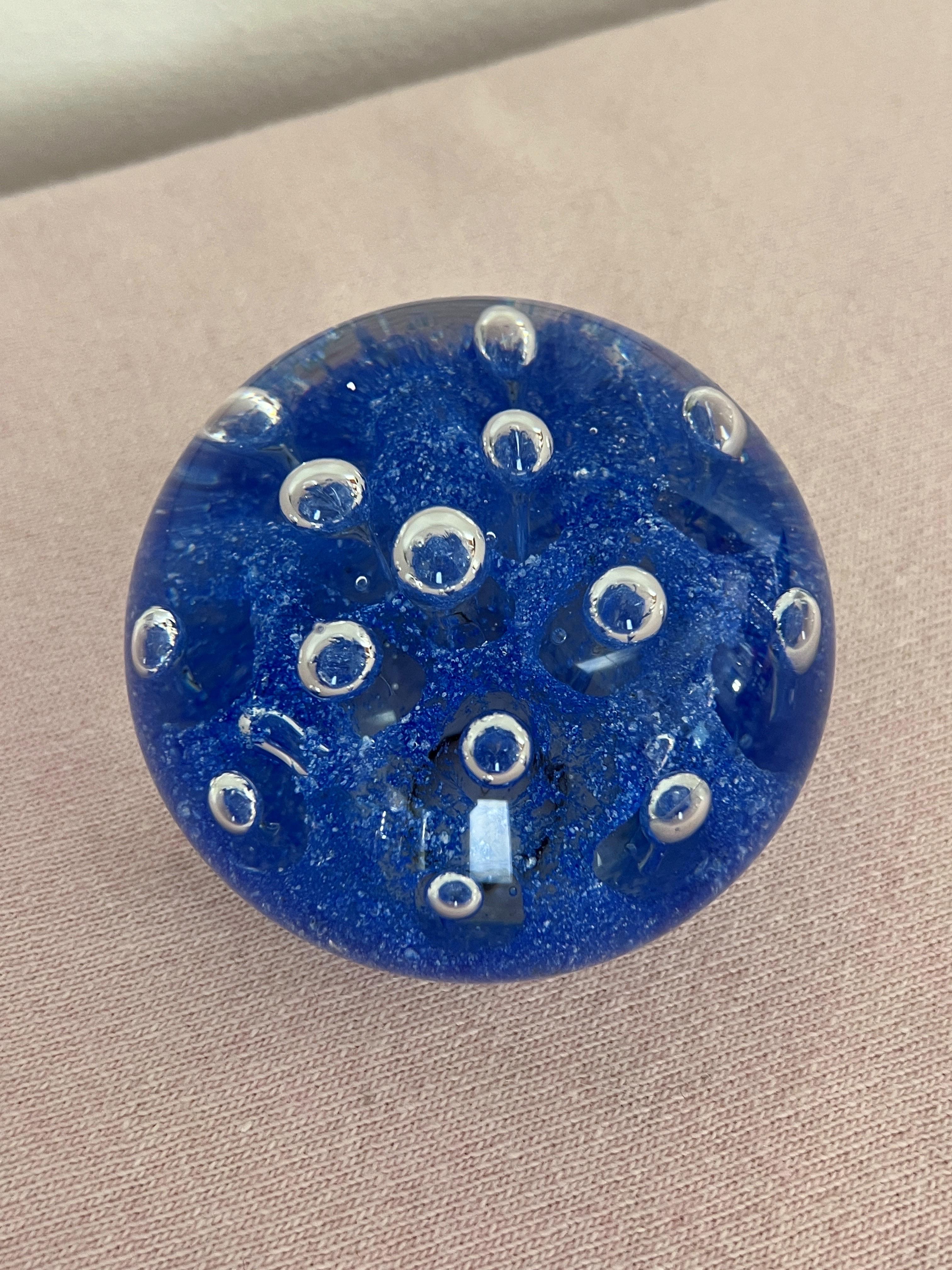 Ce superbe presse-papier présente un magnifique design avec des bulles d'air suspendues dans le verre. Le fond intérieur de la pièce est en verre bleu riche, où les bulles sont soigneusement placées, tandis que le reste du presse-papiers est en