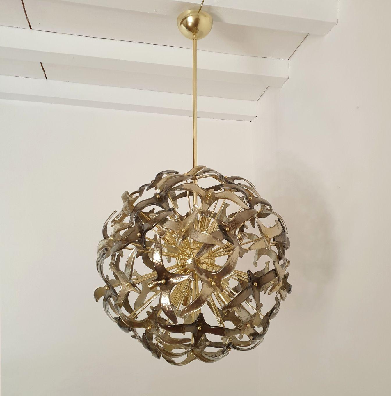 Large Murano glass sputnik chandelier attributed to Mazzega, circa 1980s, Italy.
The chandelier has a polished brass frame, with 12 lights, rewired for the US with Candelabra base sockets or E12.
The Murano glasses represent stylized birds in two