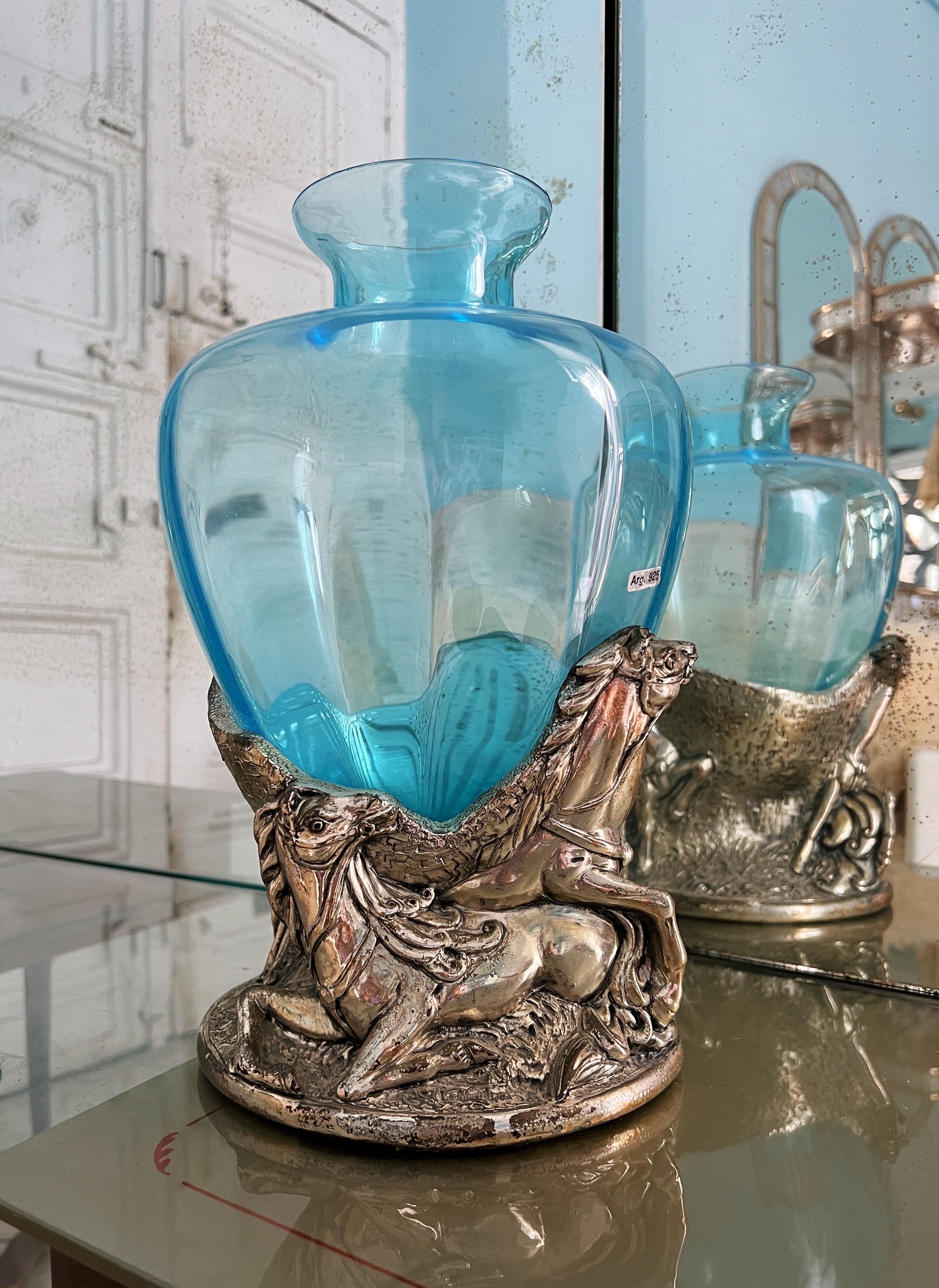 Diese exquisite Murano-Vase aus der Mitte des Jahrhunderts ist in einem auffälligen Himmelblau gehalten und ziert eine elegante Skulptur mit Pferden. Es wird angenommen, dass die Vase mit 925er Silber beschichtet ist, obwohl die Stempel auf der Vase