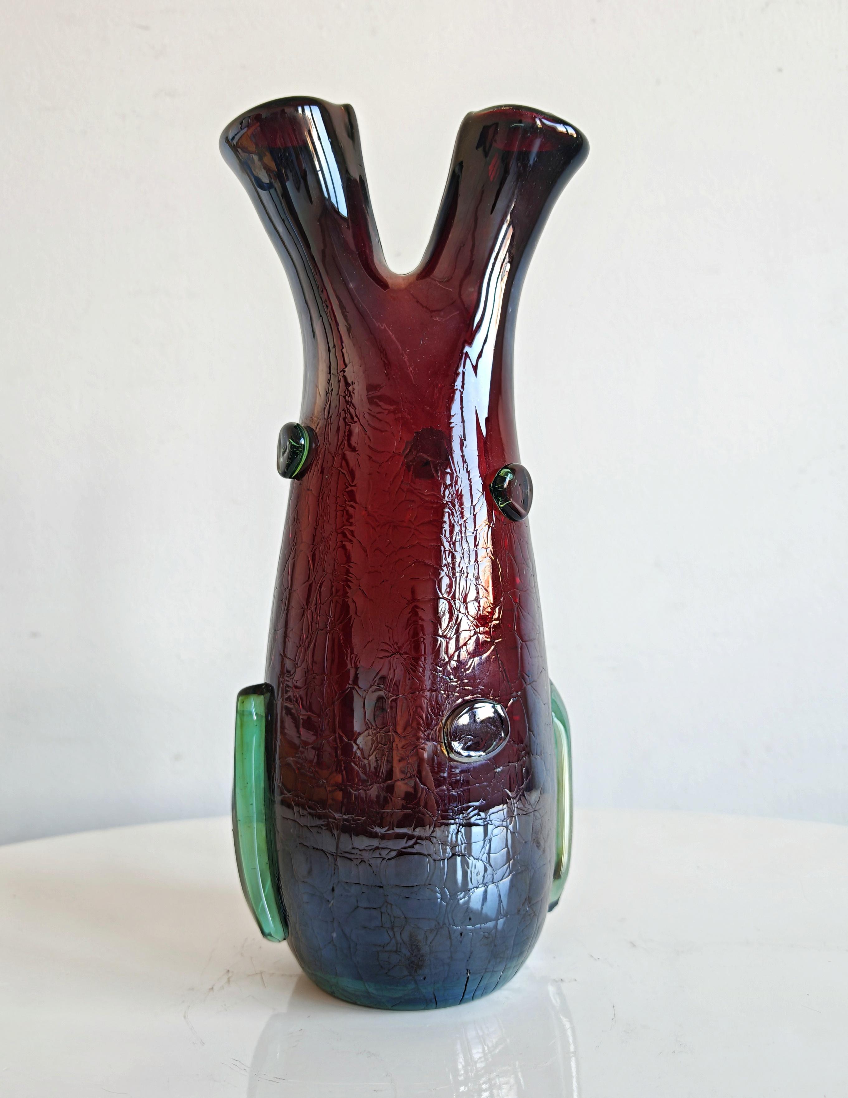 In this listing you will find a stunning Mid Century Modern mouth-blown Murano glass vase with an intriguing shape that resembles the heart. It features a striking combination of colors, primarily a deep burgundy or red color that transitions into a
