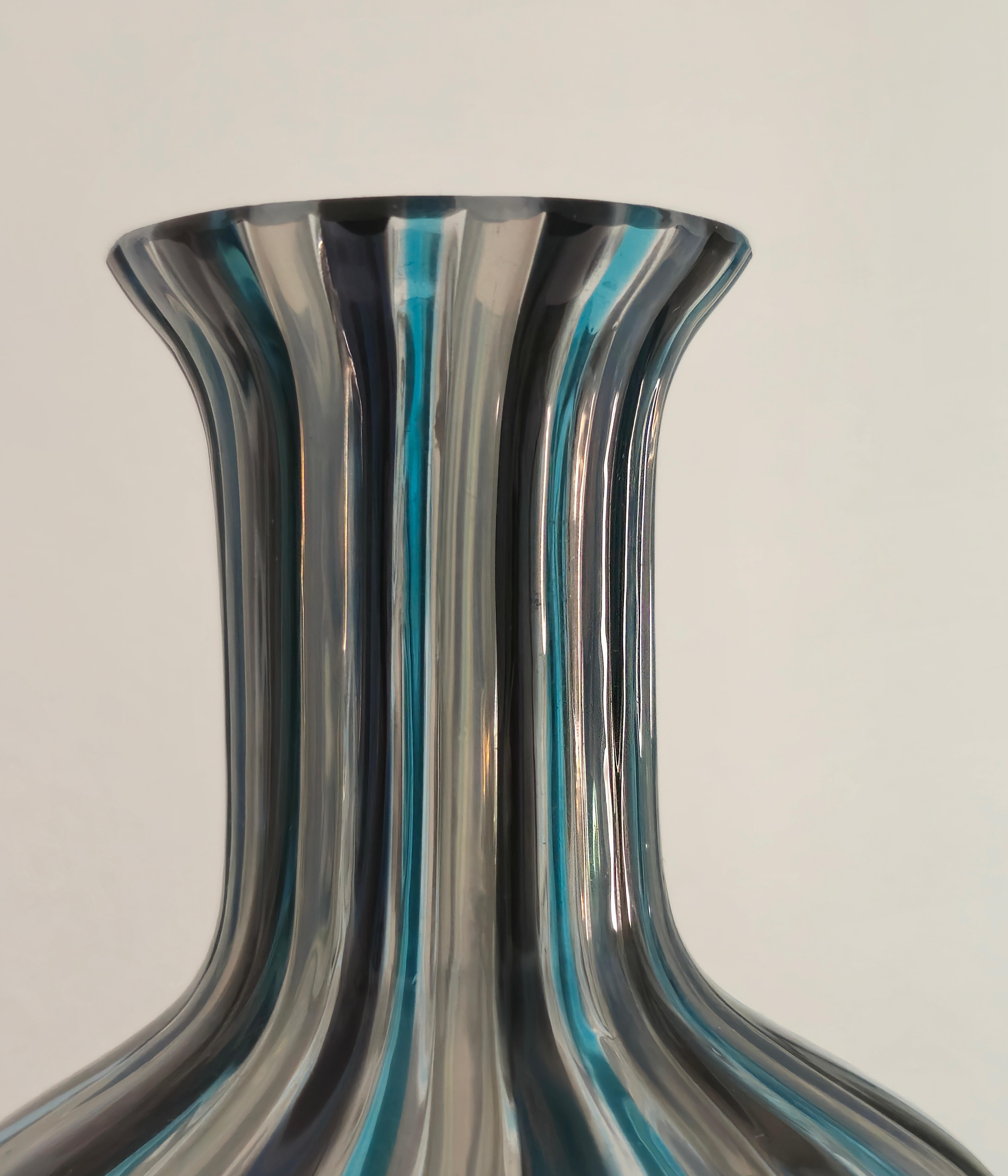 Produzione Salviati & C. Vaso in vetro soffiato decorato con canne verticali definite a mano con nastri nei toni del blu, grigio e bianco opalescente con collo basso. Label di produzione.
Nel 1859, l'avvocato vicentino Antonio Salviati iniziò la sua