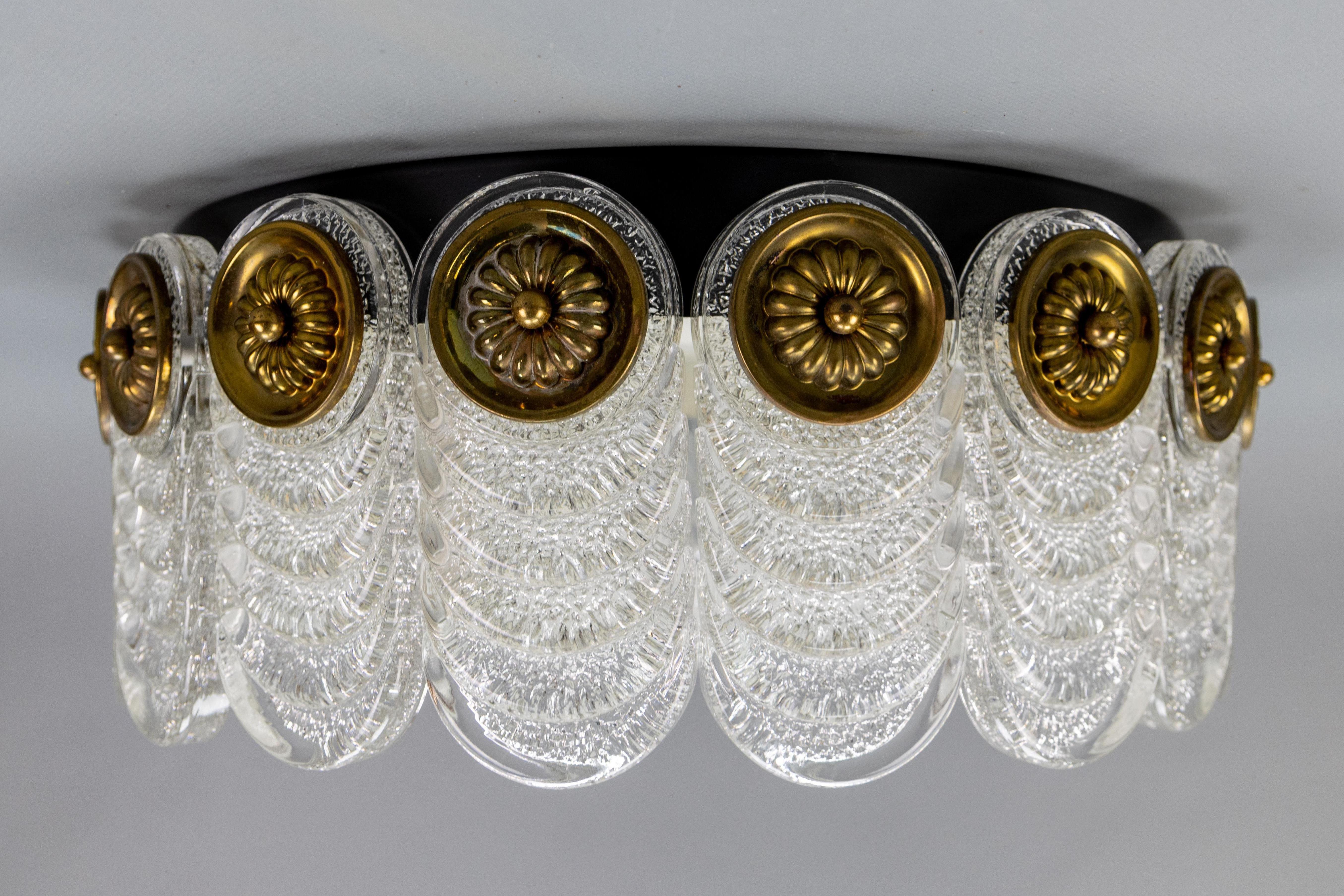 An elegant Mid-Century Modern four-light round ice glass flush mount from the 1970s by Kaiser Leuchten, Germany. 
The round metal base is adorned with 18 thick, textured Murano ice glass pendants, fastened with decorative brass mounts. The light