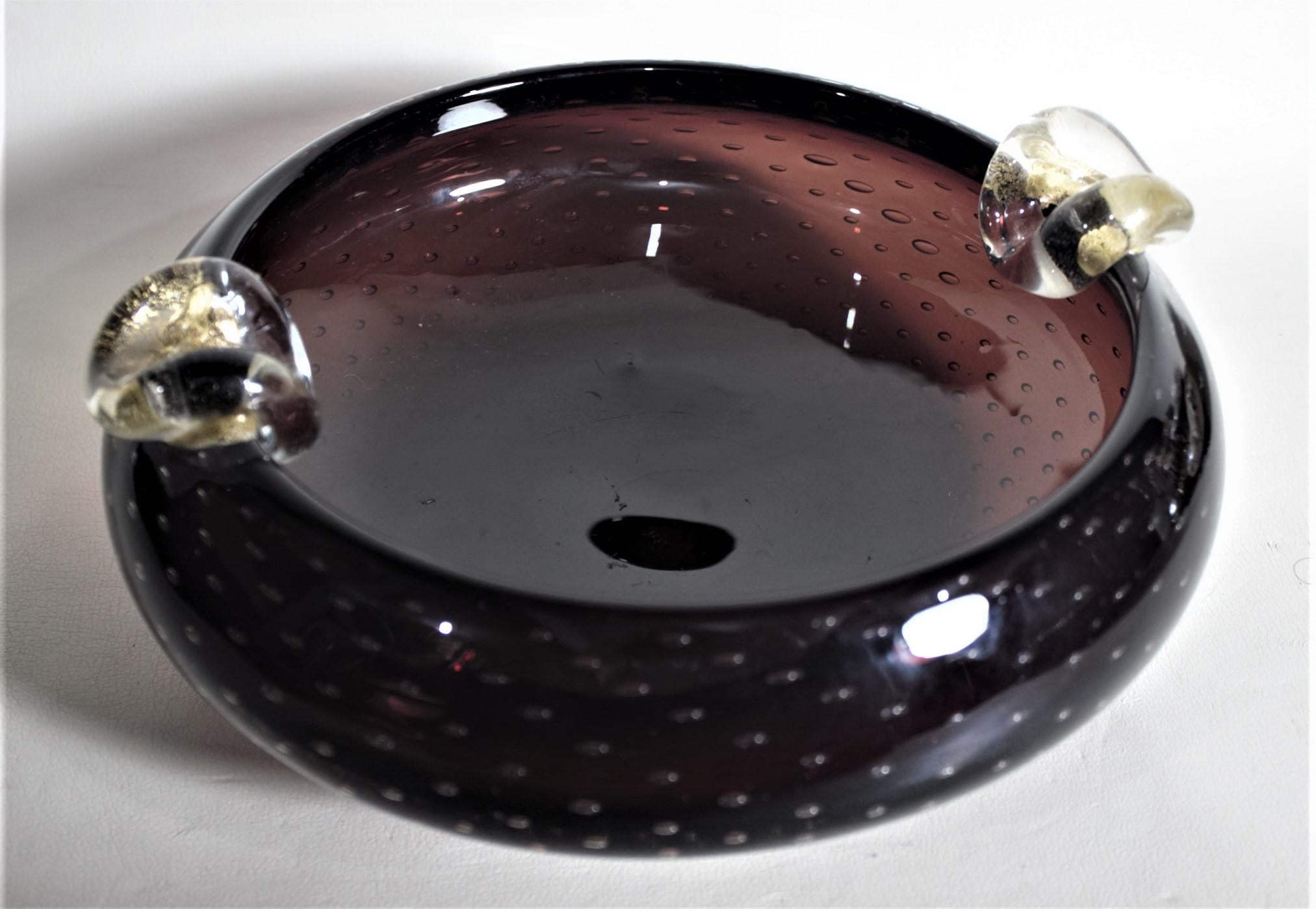 This Mid-Century Modern unique art glass cigar ashtray is unsigned, but presumed to have been made in Murano Italy in circa 1965 in the style of Angelo Seguso. The body of the ashtray is done in amethyst glass with a series of controlled bubbles