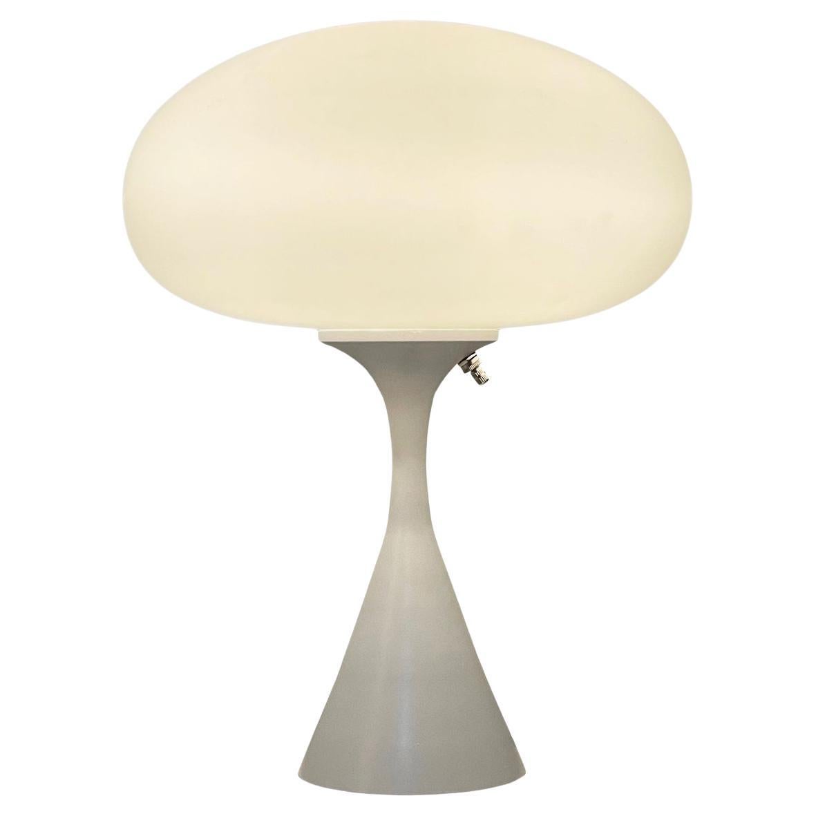 A handsome table lamp in a conical mushroom form after Laurel Lamp Company. The lamp features a cast aluminum base with a white powder coat and a mouth blown frosted glass lamp shade.