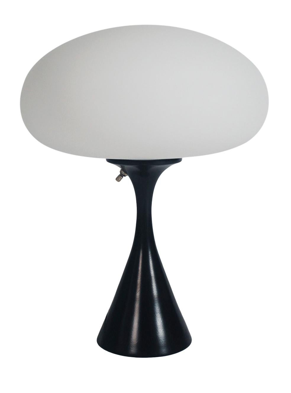 A handsome table lamp in a conical mushroom form after Laurel lamp Company. The lamp features a cast aluminum base with a black powder coat and a mouth blown frosted glass lamp shade.