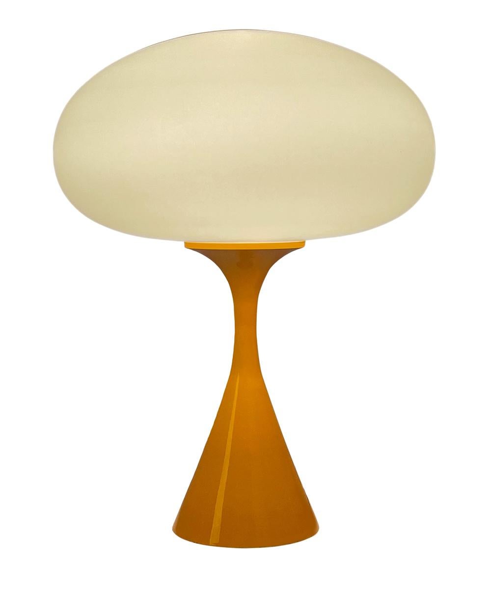 A handsome table lamp in a conical mushroom form after Laurel lamp Company. The lamp features a cast aluminum base with an orange powder coat and a mouth blown frosted glass lamp shade.