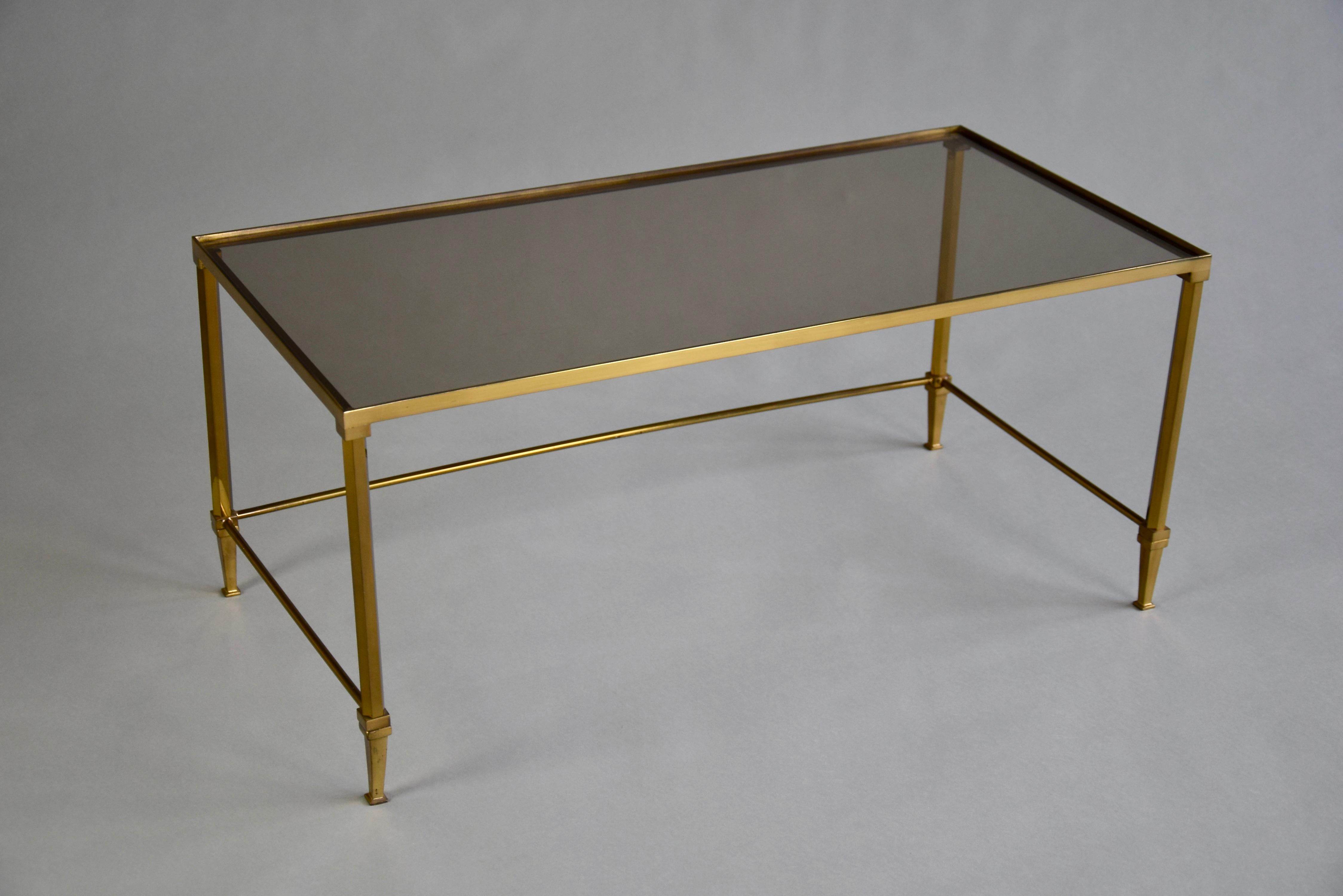 Stylish and sophisticated set of one coffee table and two nesting tables. This elegant set is made of brass in combination with fume glass. The brass has the perfect patina. The big table measurers L.76 x D.38 x H.34 cm and the two nesting tables