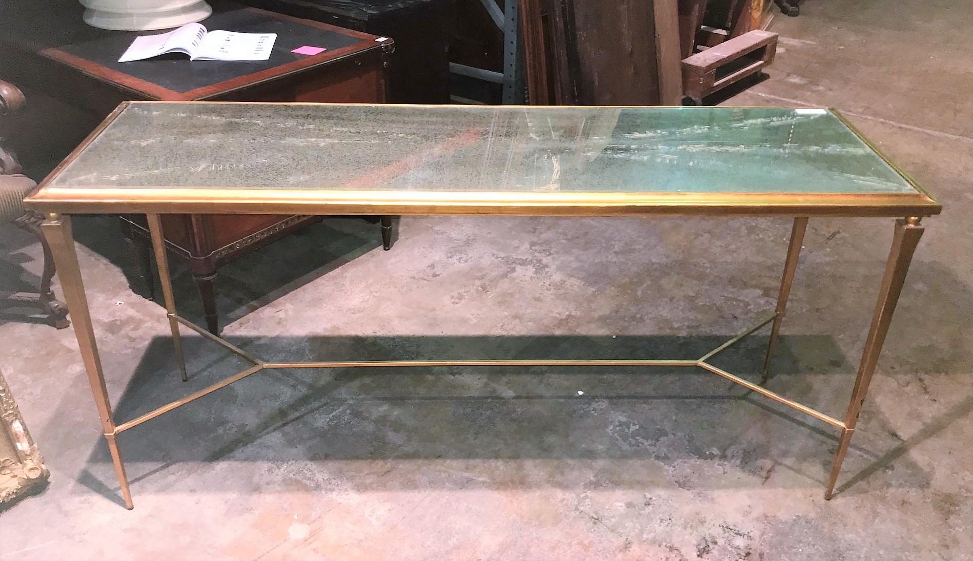 Mid-Century Modern neoclassical design narrow console table on tapered legs and connecting stretcher. Custom crafted piece exhibiting a rich gold leaf patinated metal finish, and having an antique mirrored glass top,

circa 1960.



 