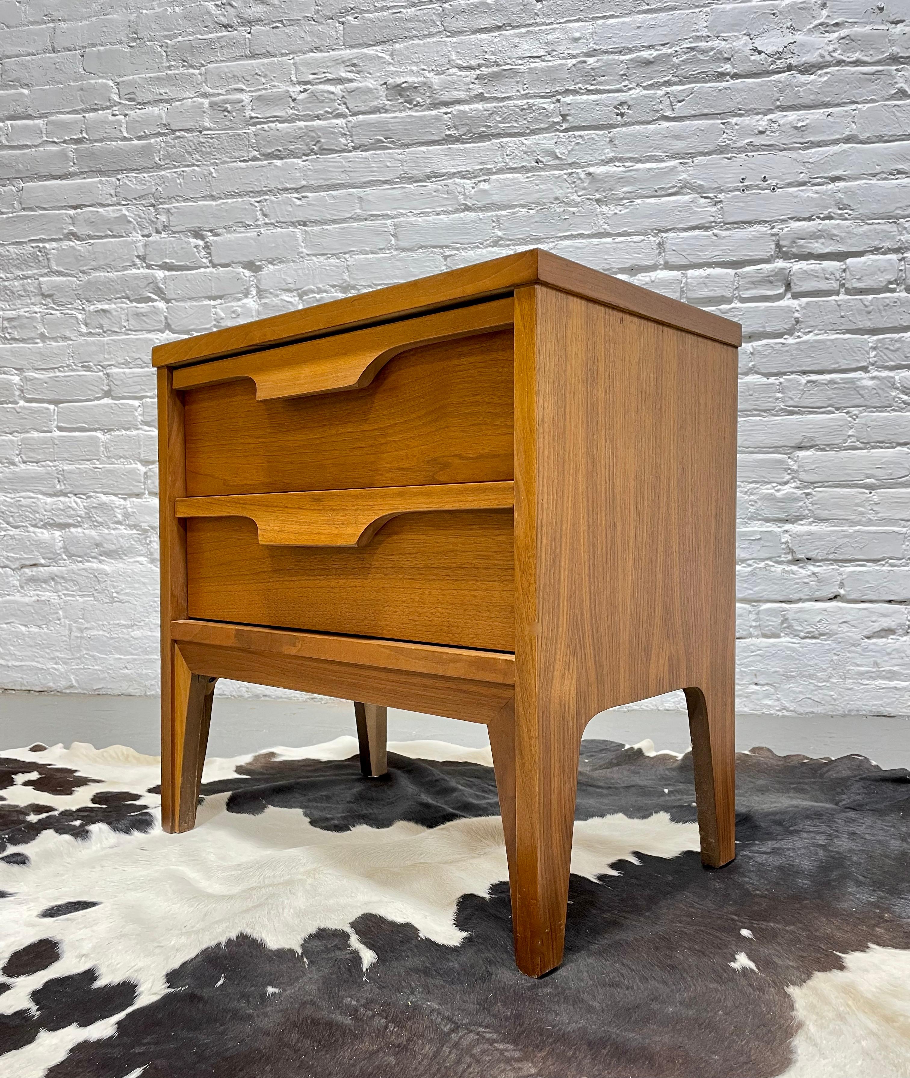 Mid Century Modern Walnut Nightstand by Johnson Carper, c. 1960's.  Beautiful architectural detailing with sculpted handpulls. Very nice vintage condition with minimal wear from age and use. Laminate woodgrain tabletop, perfect for sustaining a bit