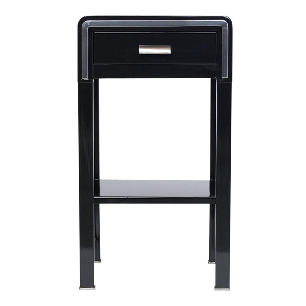 This modern side table by NY Simmons Company has been newly restored and is made out of a metal and steel combination with a polished chrome finish. This piece features a black lacquered finish, flat chrome molding detail in the front, and a single