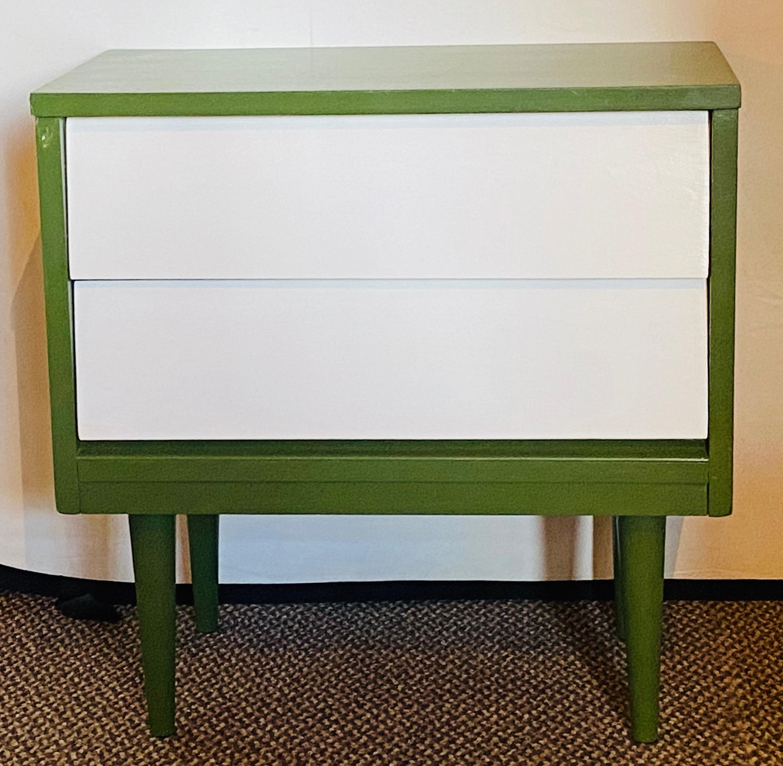 Pair of Mid-Century Modern nightstands or lamp tables. Two-tone paint decorated having a pair of white slanted drawers with hidden pulls on an olive green case. The whole supported by tapering legs. Perfect for multiple use such as side tables, lamp