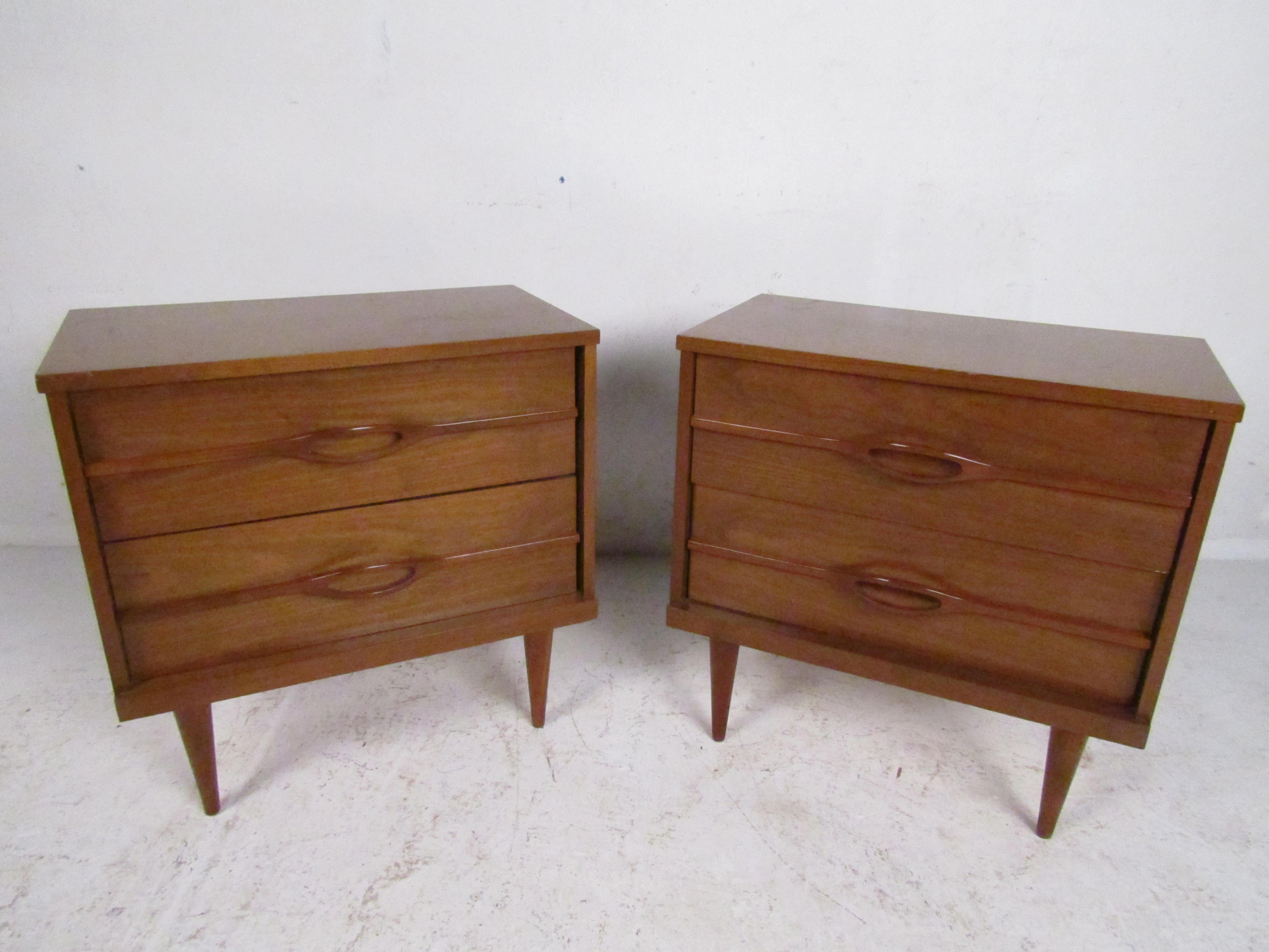 Stylish pair of Mid-Century Modern nightstands. Sturdily constructed frames with a nice walnut veneer exterior. Two drawers on each Stand with sculpted drawer pulls. This pair is sure to be a nice addition to any modern interior. Please confirm item