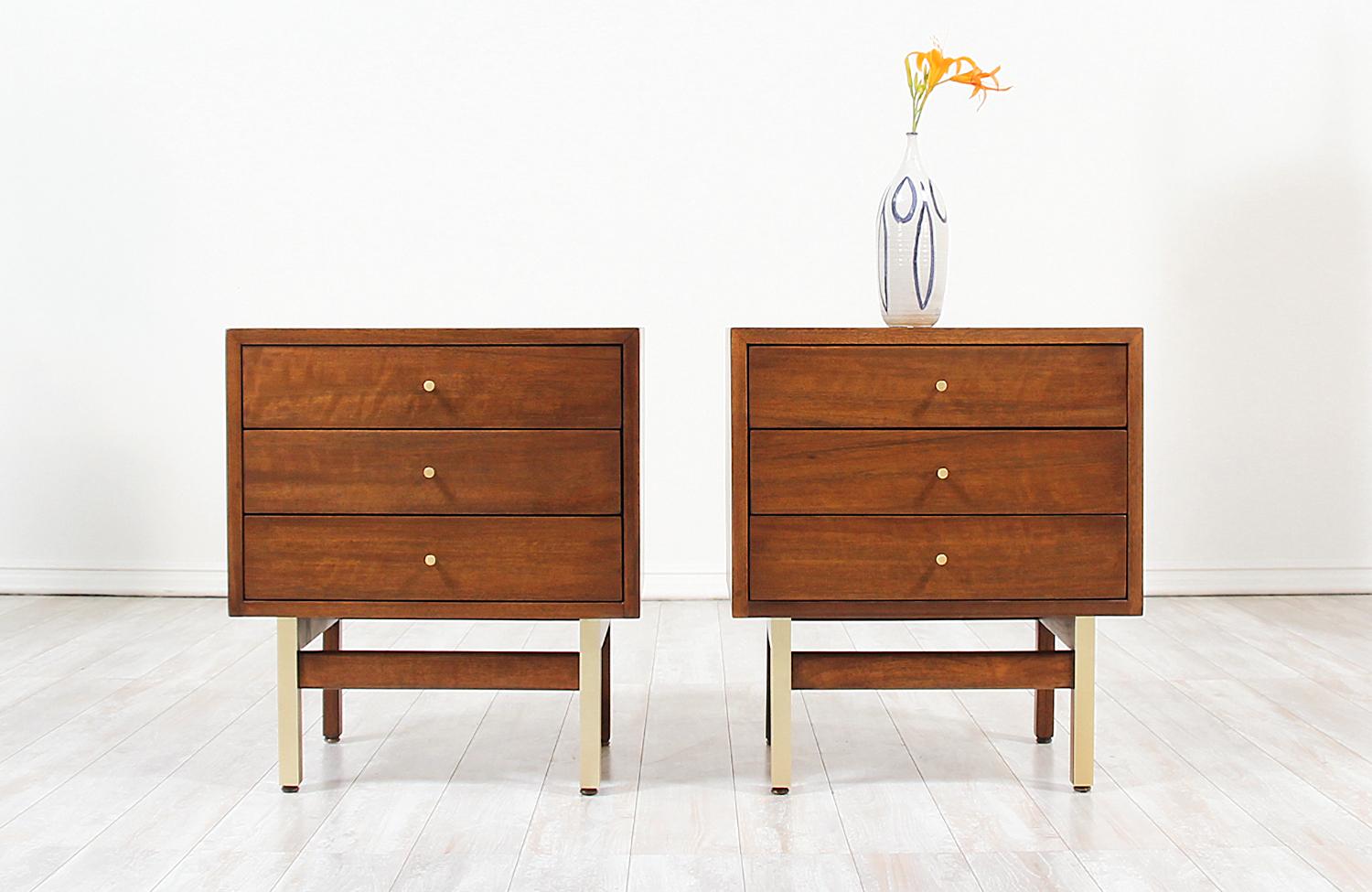 Stylish pair of modern nightstands designed and manufactured by American of Martinsville in the United States, circa 1960s. These lovely night stands feature a sturdy finished walnut wood case standing on squared legs that are trimmed with lovely