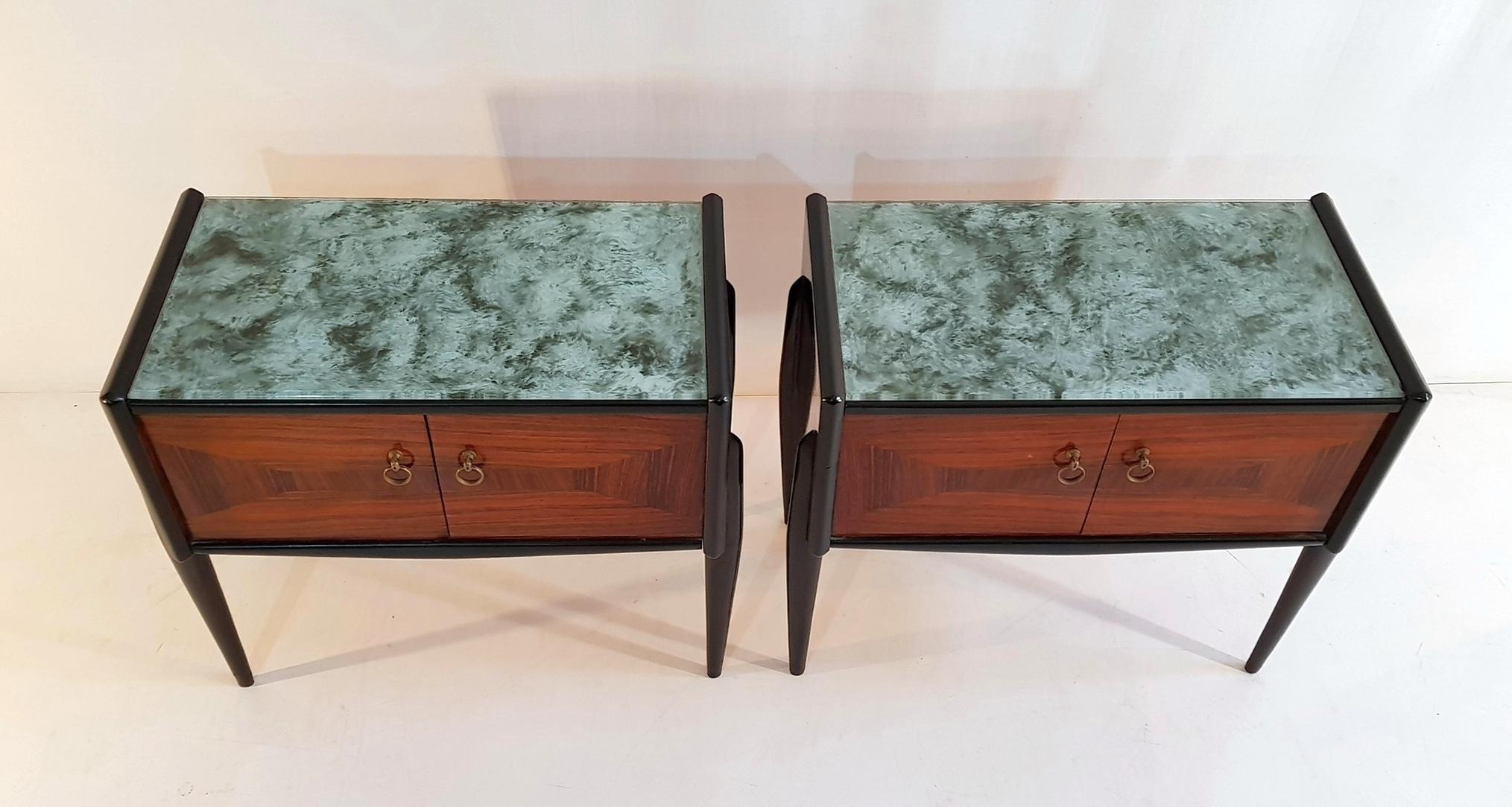 A pair of 1950s beautiful nightstands in jacaranda and with sculptural legs. Each nightstand has a pair of doors with an intricate marquetrly design and glass top in glass with details in brass. In excellent condition.