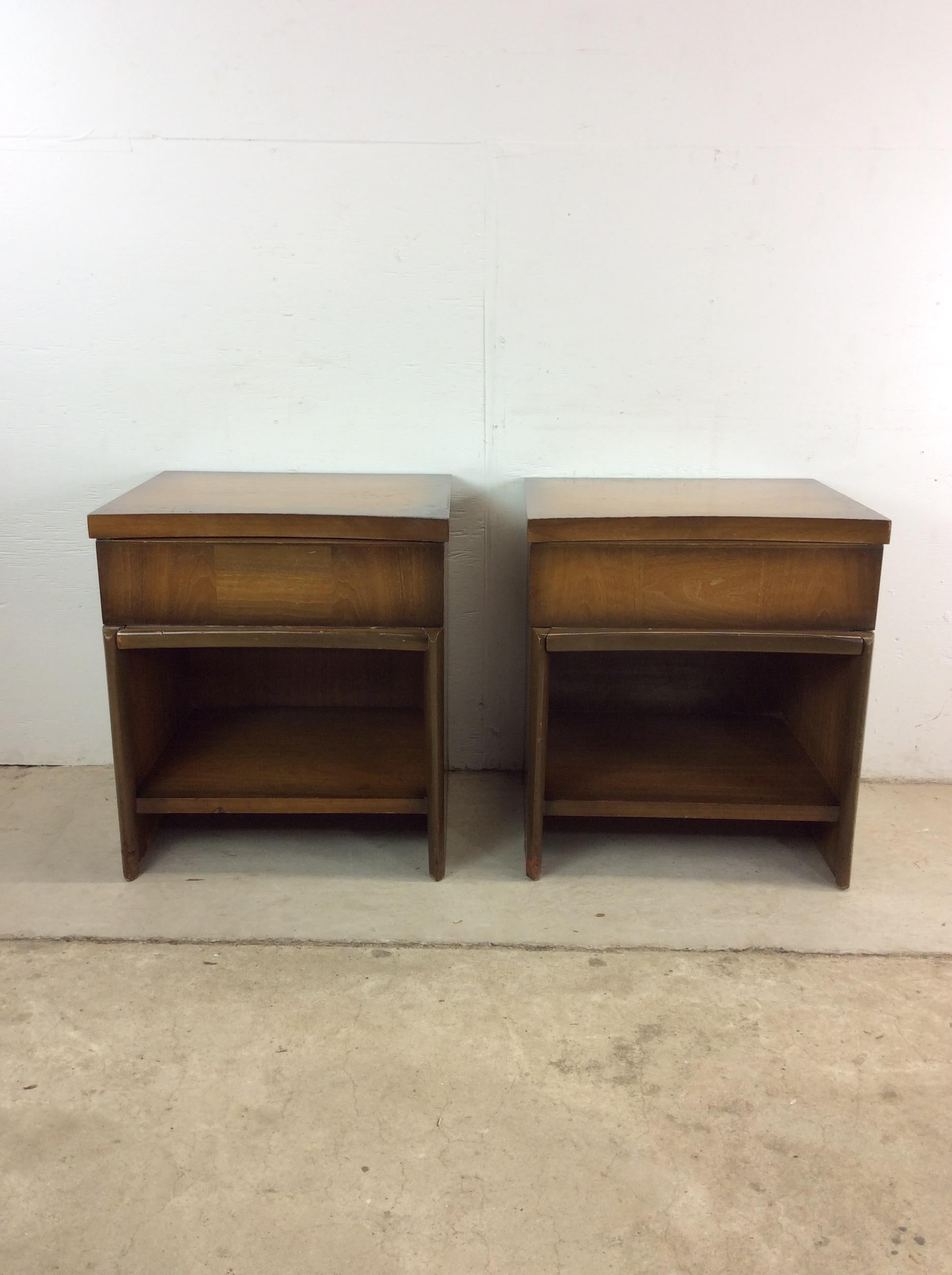 This pair of mid century modern nightstands feature hardwood construction, walnut veneer with original finish, single dovetailed drawer, opened storage shelf, and sled style legs.  Matching highboy and lowboy dresser with mirror available