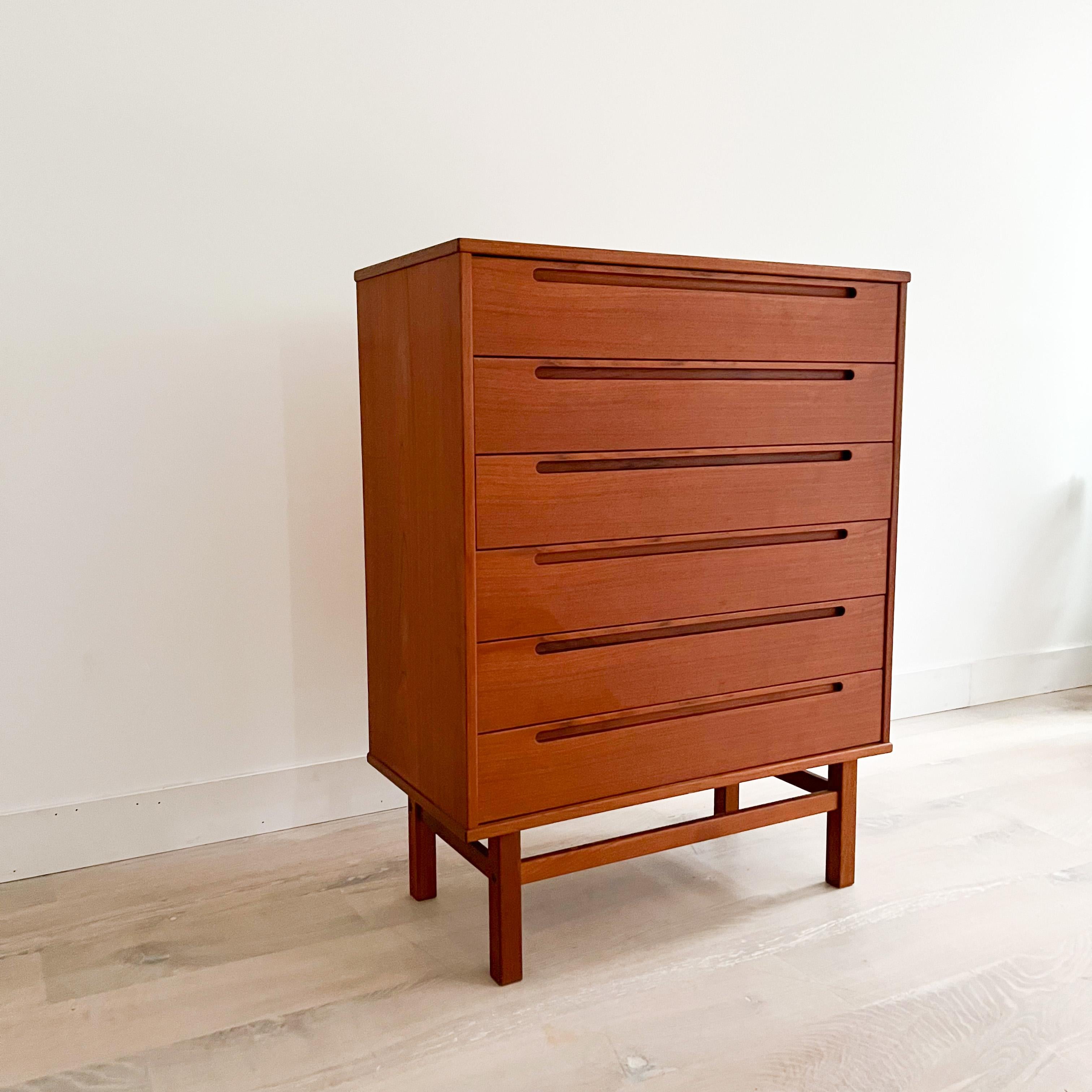 Mid-Century Modern danish teak highboy dresser designed by Nils Jonsson. Some light scuffing/scratching/small areas of veneer repair from age appropriate wear. The drawers open and close with ease. Nice inset sculpted drawer pulls.