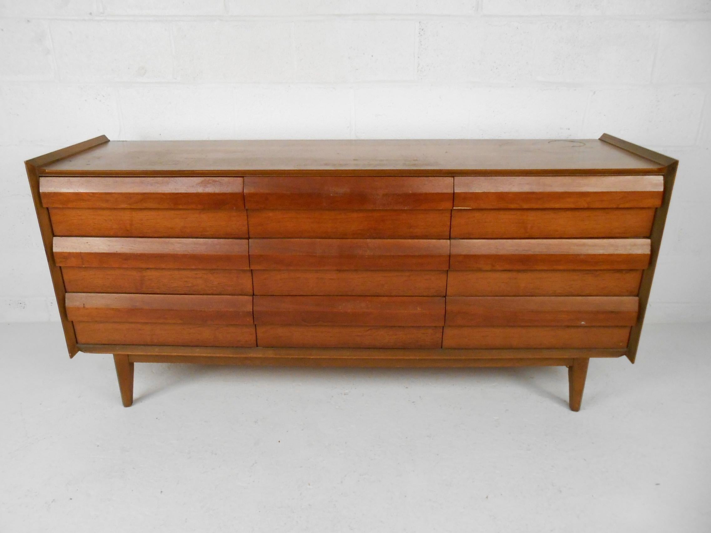 Impressive midcentury nine-drawer dresser manufactured by Lane Furniture Company in Altavista, Virginia. Nine spacious dovetail-jointed drawers with interesting sculpted drawer pulls. Raised edges on either side of the piece provide a stylish accent