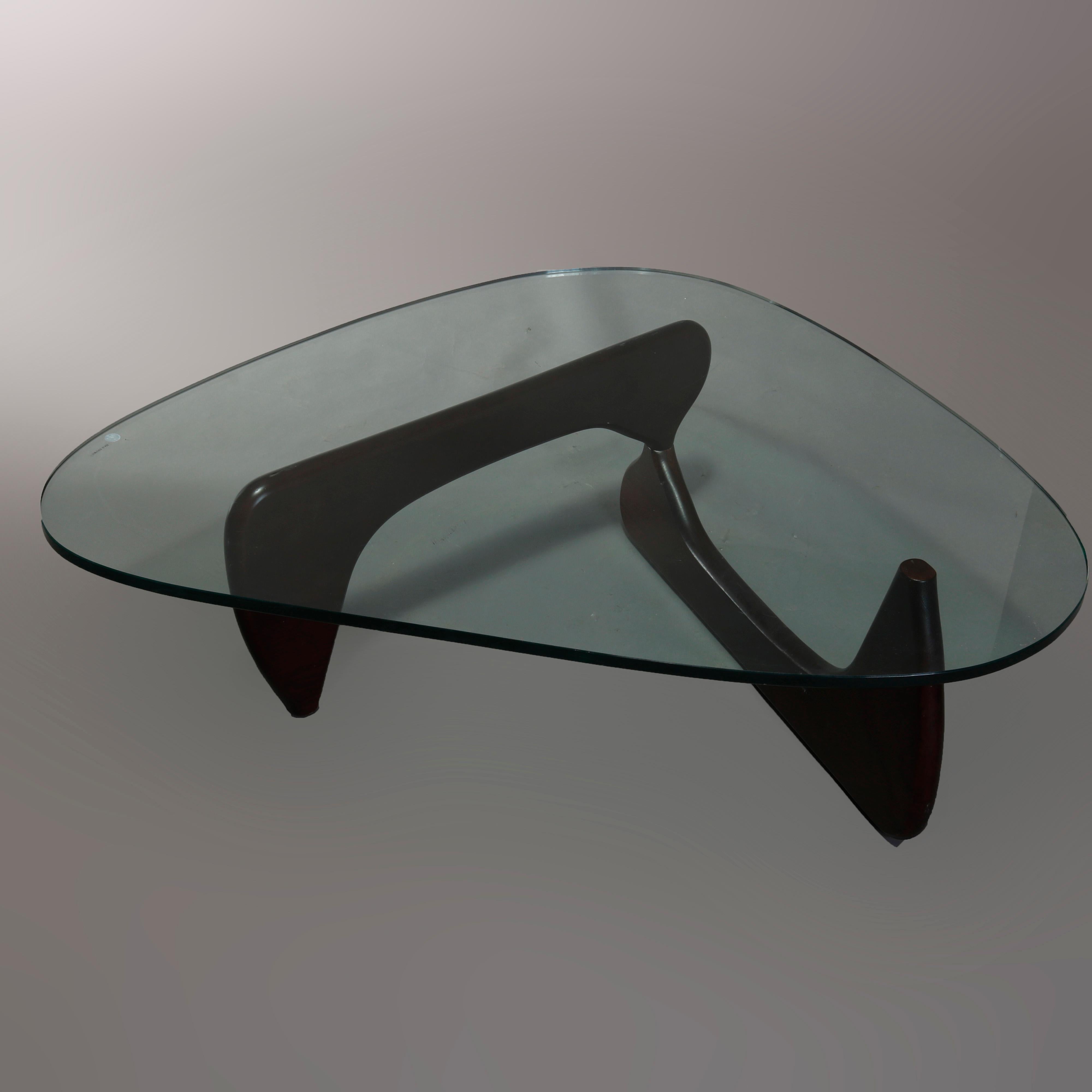 Vintage Mid-Century Modern Noguchi sculptural rudder form coffee table offers stylized triangular glass top over walnut base, attributed to Herman Miller, 20th century.

Measures: 15.75