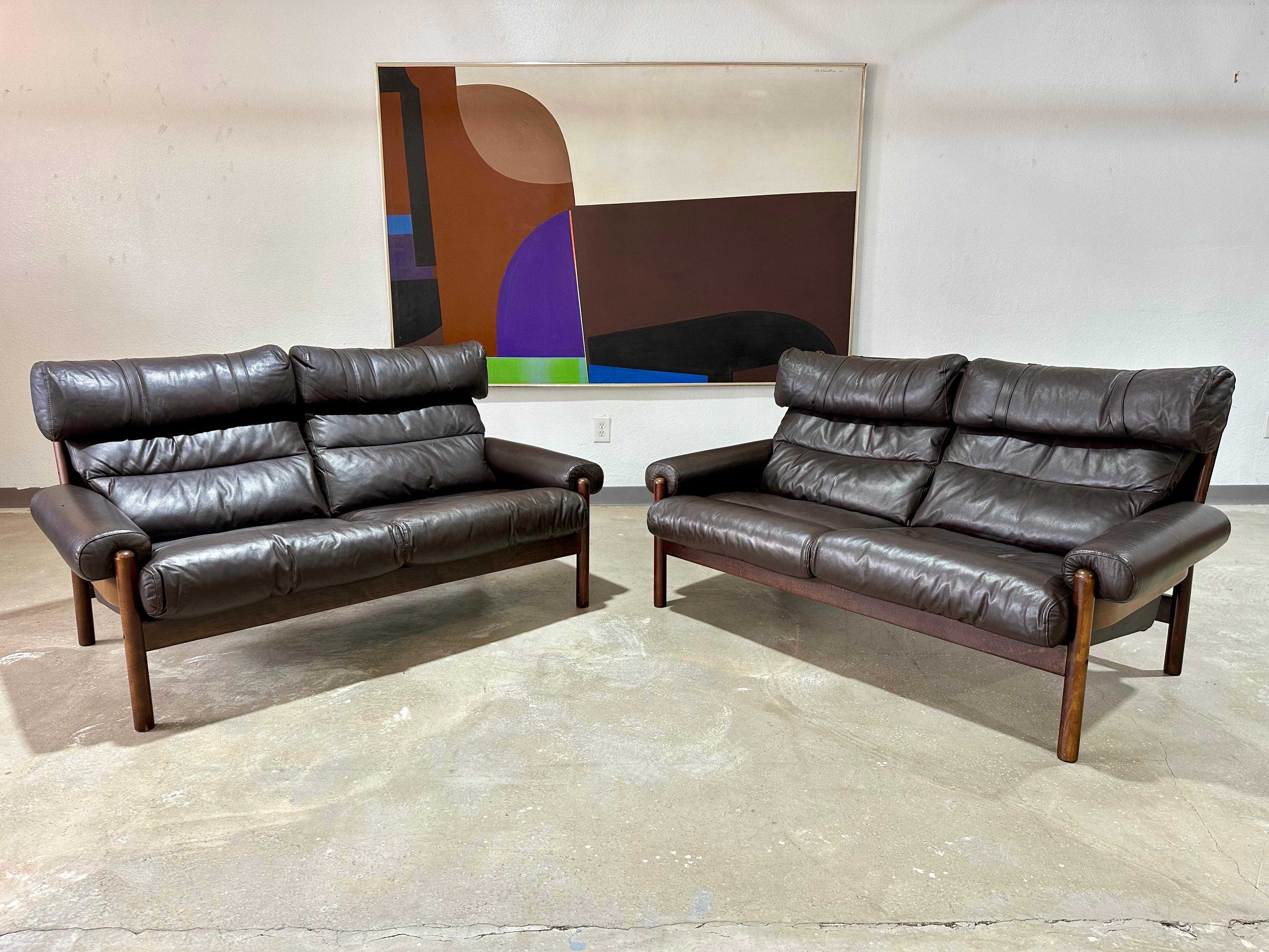 Vintage 1970's Scandinavian Loveseat im Stil des Inca von Arne Norell. Ausgestattet mit dem originalen dunkelbraunen Leder auf Buchenholzrahmen mit Leinwandrücken. Hohe Rückenlehne mit Kopfstützenkissen, die mit Gurtdetails verziert sind. Ein
