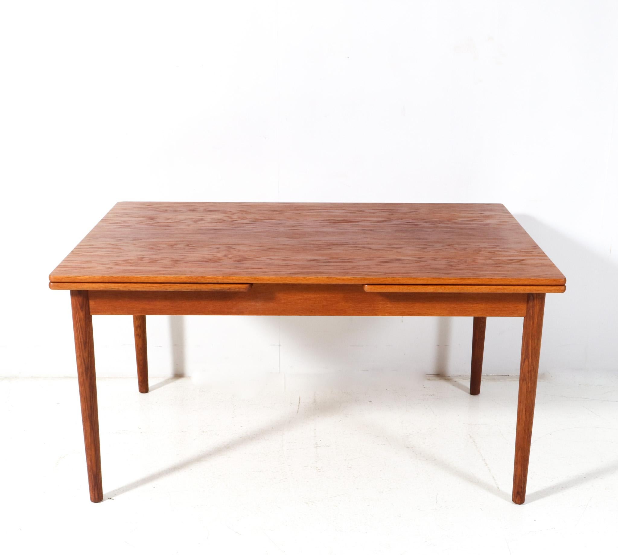Stunning and rare Mid-Century Modern AT-316 dining room table.
Design by Hans J. Wegner for Andreas Tuck Møbelfabrik.
Striking Danish design from the 1960s.
Solid oak frame with four tapered legs and original oak veneered top and two extensions.
The