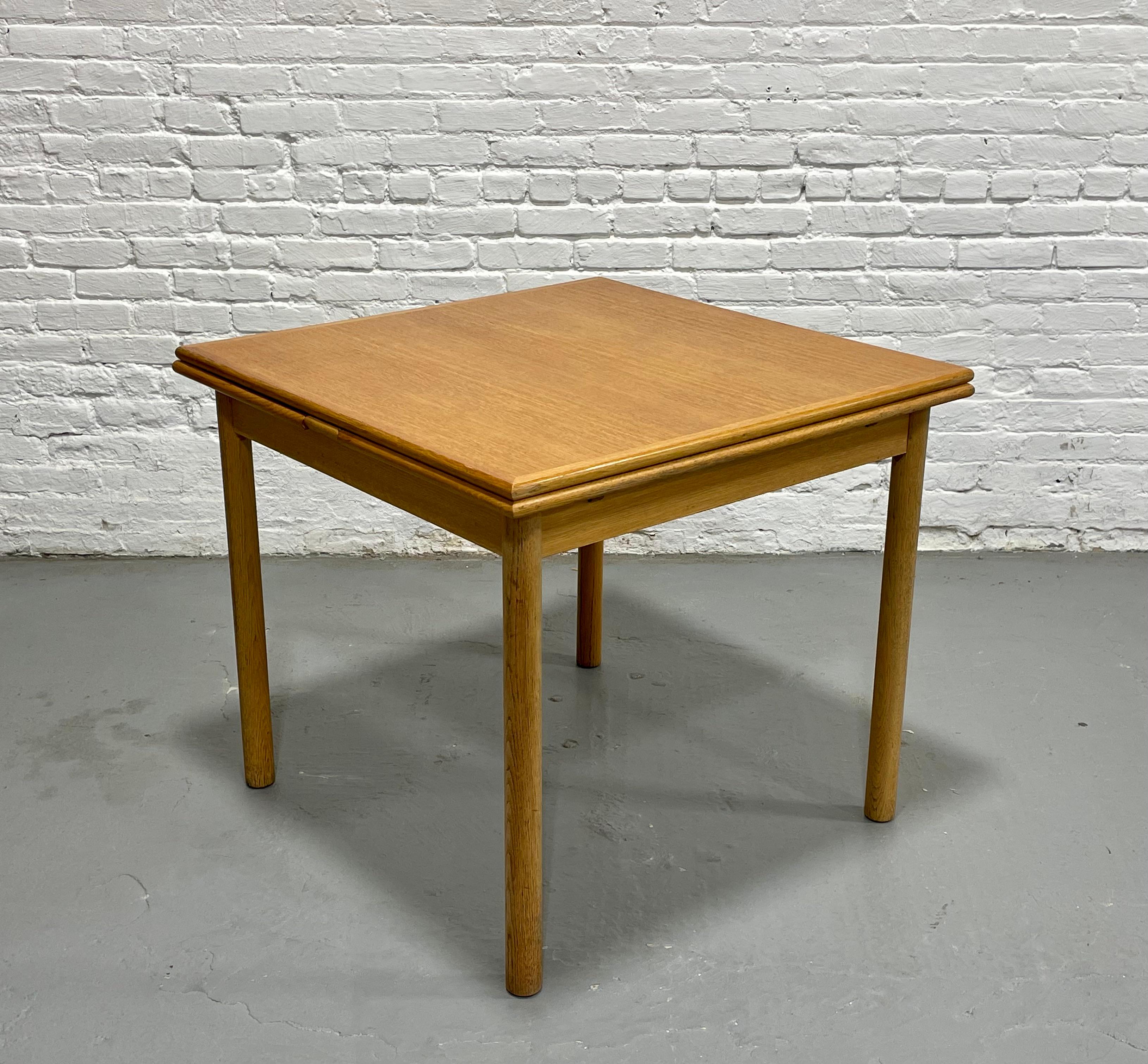 TABLE À DINER EN CHÊNE, de taille d'appartement, de style moderne du milieu du siècle, avec deux feuilles cachées. La table est d'une taille compacte parfaite pour les petits espaces et dispose de deux feuilles cachées qui se placent sous le plateau