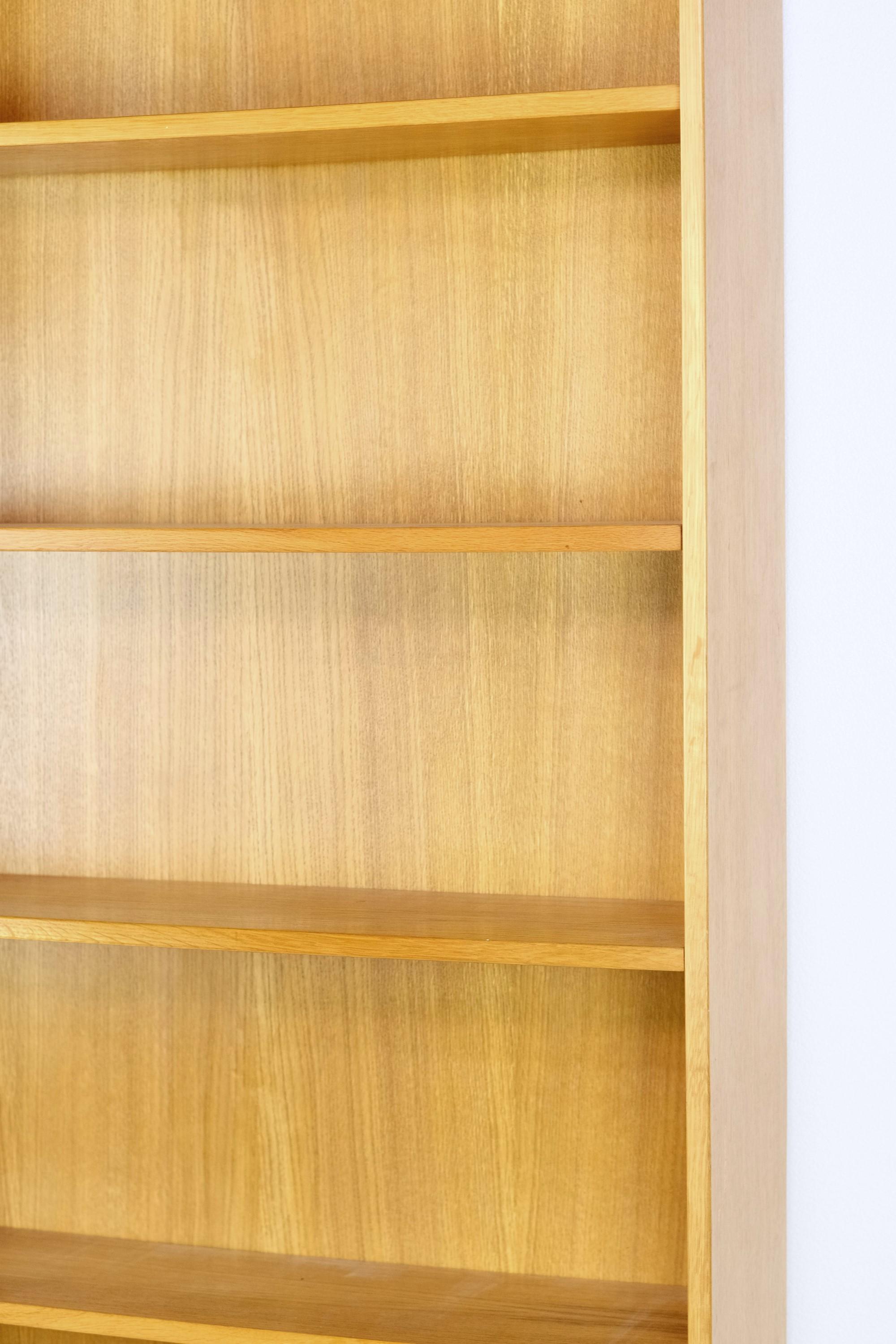 Cette bibliothèque en bois plaqué chêne de style moderne du milieu du siècle comporte six étagères réglables. Elle faisait autrefois partie de la bibliothèque personnelle d'un professeur de l'université de Columbia à New York. Cette bibliothèque
