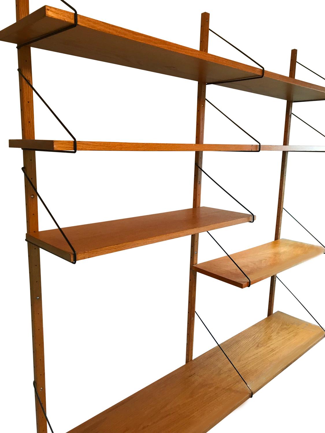 A handsome midcentury shelving unit that boasts simple design. It features oakwood components with black metal hanging hardware.