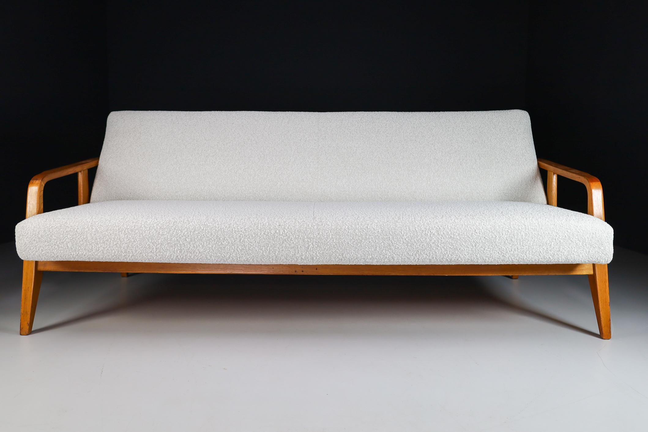 Mid-Century Modern oak sofa /daybed In new boucle upholstery wool , France 1950s. The grain of the wood is nicely visible, especially on the elegant armrests. This sofa /daybed would make an eye-catching addition to any interior such as living room,