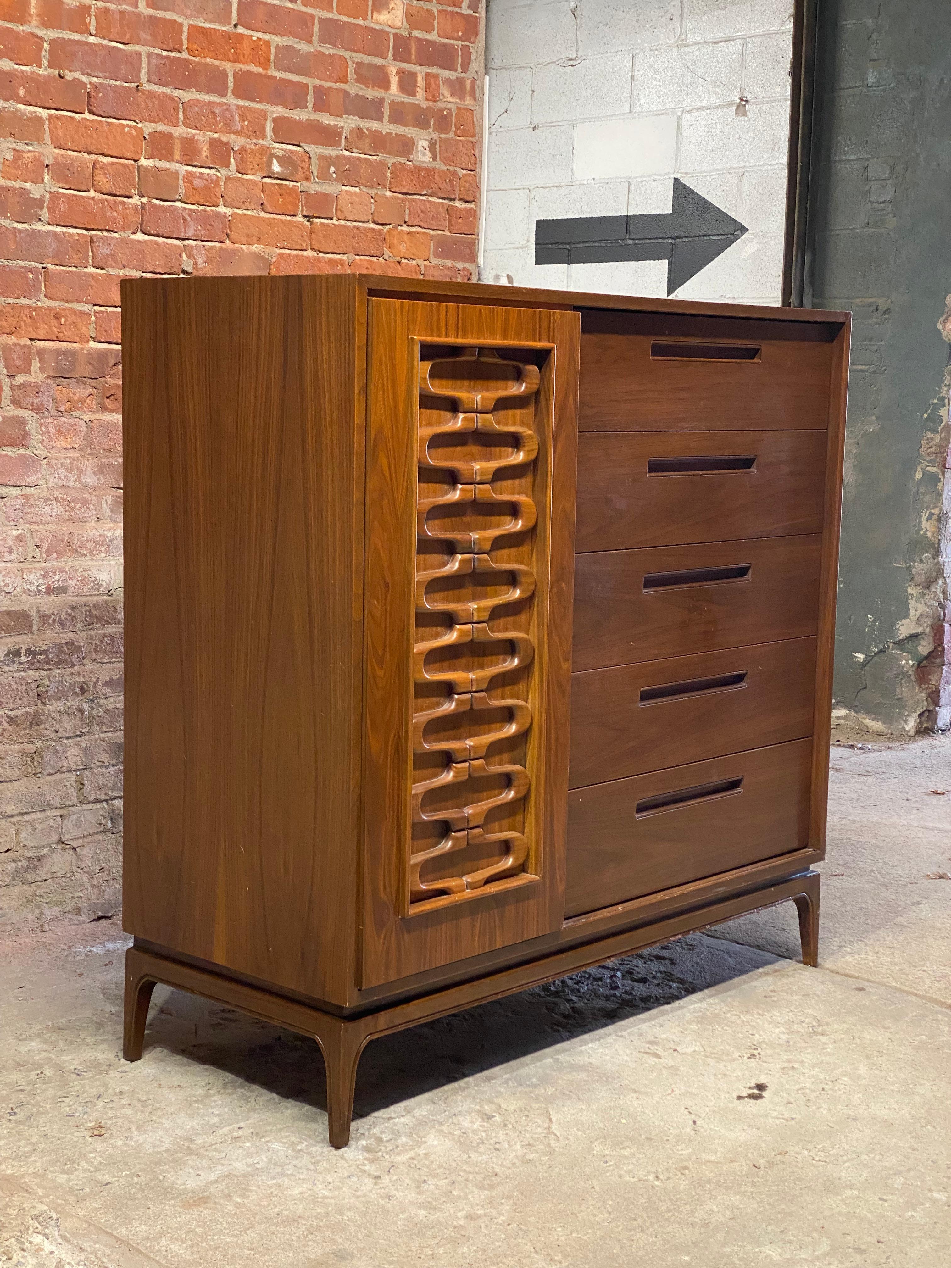 Exceptional tall walnut dresser. Circa 1960. Five by five drawer design, tapered flared legs, sliding door with a wonderful abstract design. Pieces of this size and design were often referred to as gentleman's dresser when part of a larger bedroom