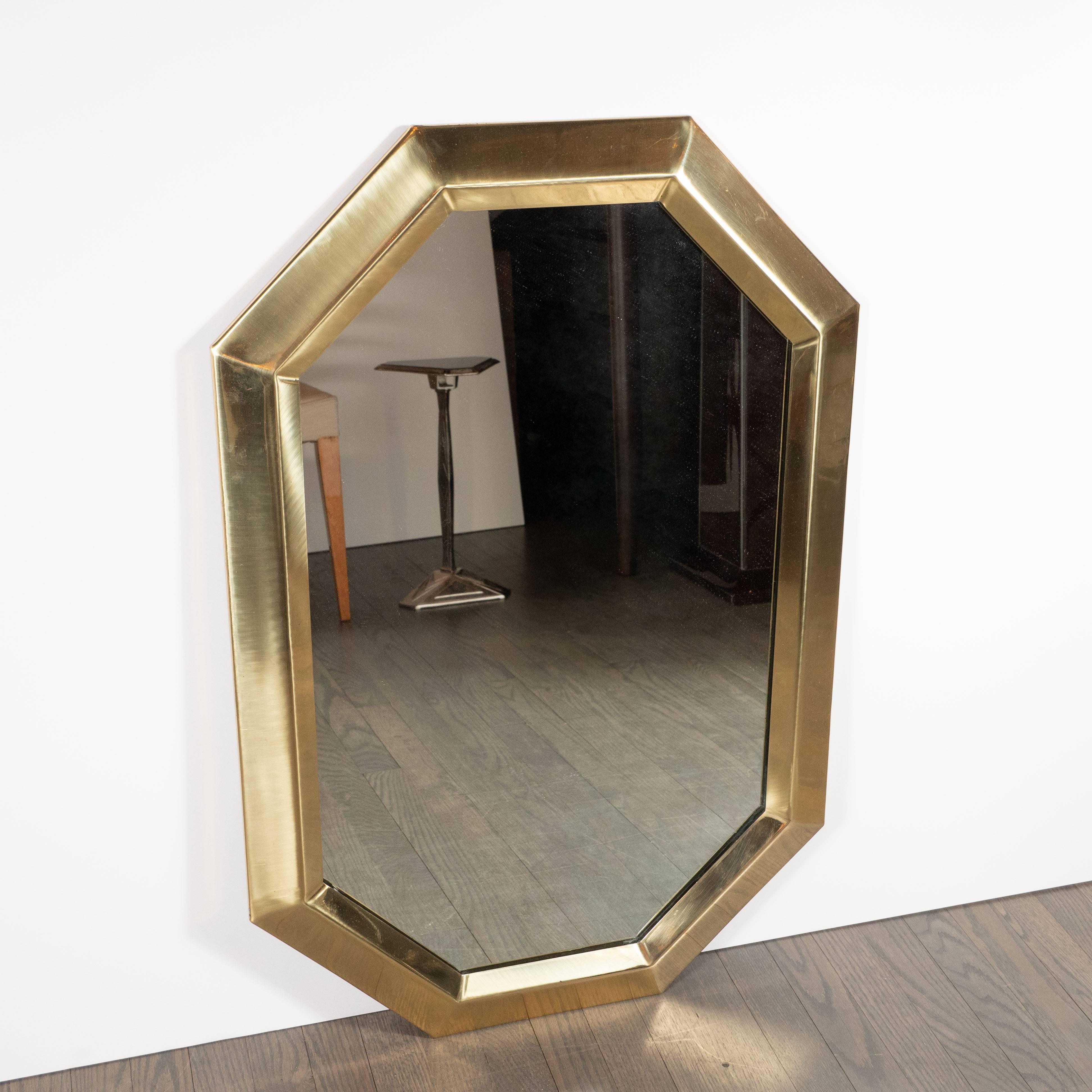 This elegant mirror was realized in the United States, circa 1970. It features an elongated octagonal brass body with raised edges, lending the piece a sculptural presence full of interesting angles and geometric forms. With its clean lines and