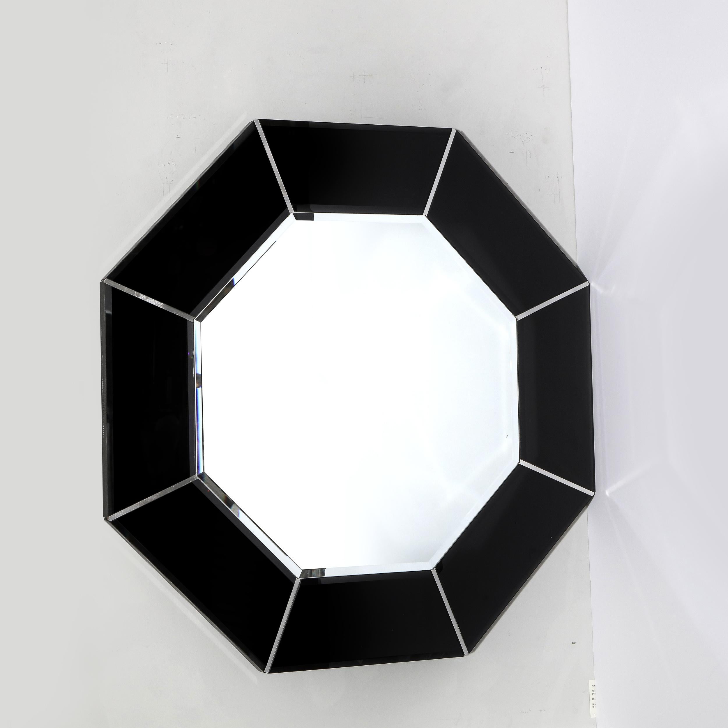 This graphic and refined Mid-Century Modern mirror was realized in the United States circa 1970. It feature an octagonal body with a smoked exterior composed of adjoining panels of graphite hued mirror separated by rectangular brushed aluminum