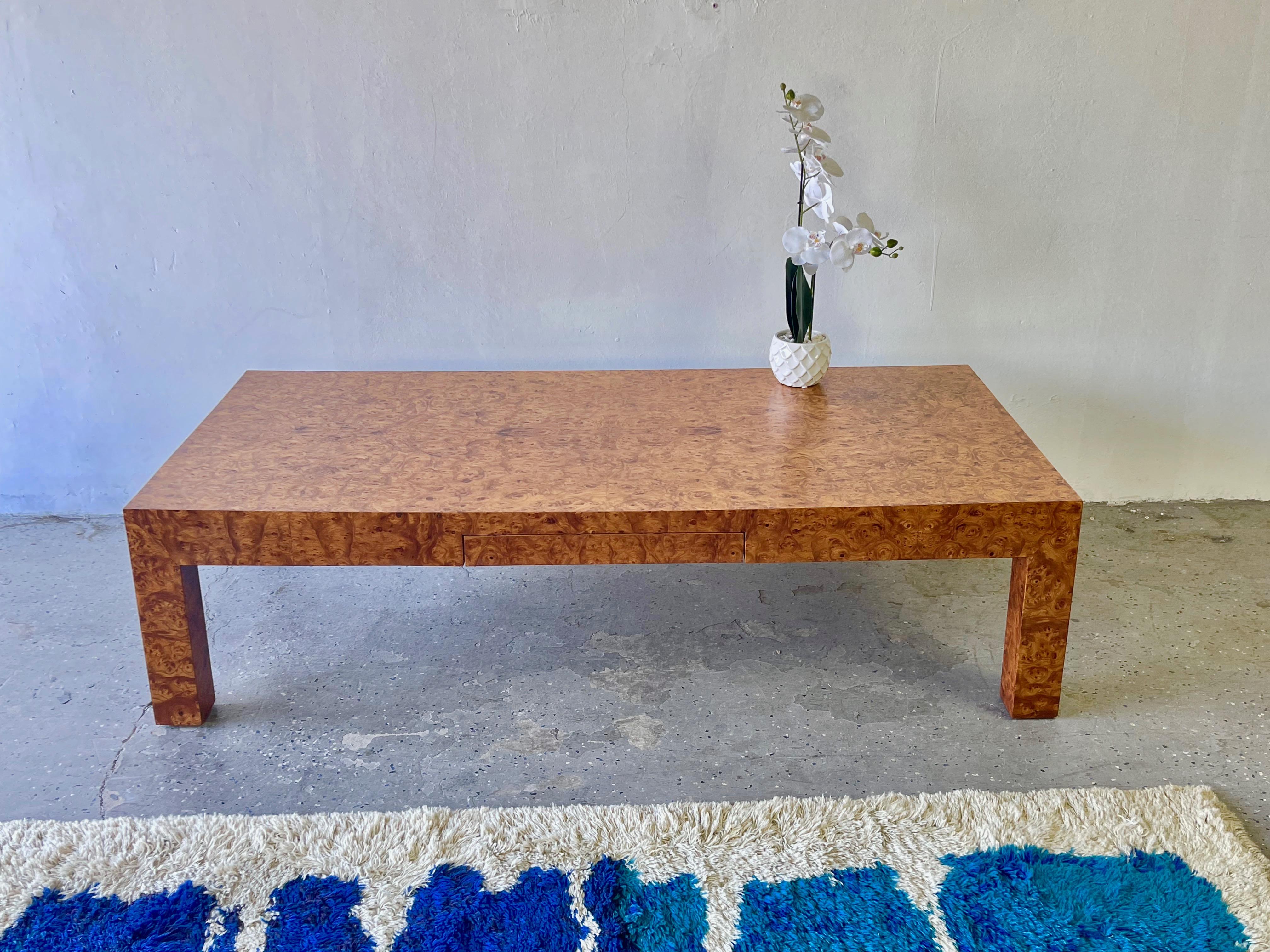 A stunning olive burl wood coffee table- beautifully crafted in the 1970s, this piece stands long and low on thick legs and will be a timeless addition to your living room. Has a 1 drawer on the side. 

Measures: 60 wide 28 deep 16 high.