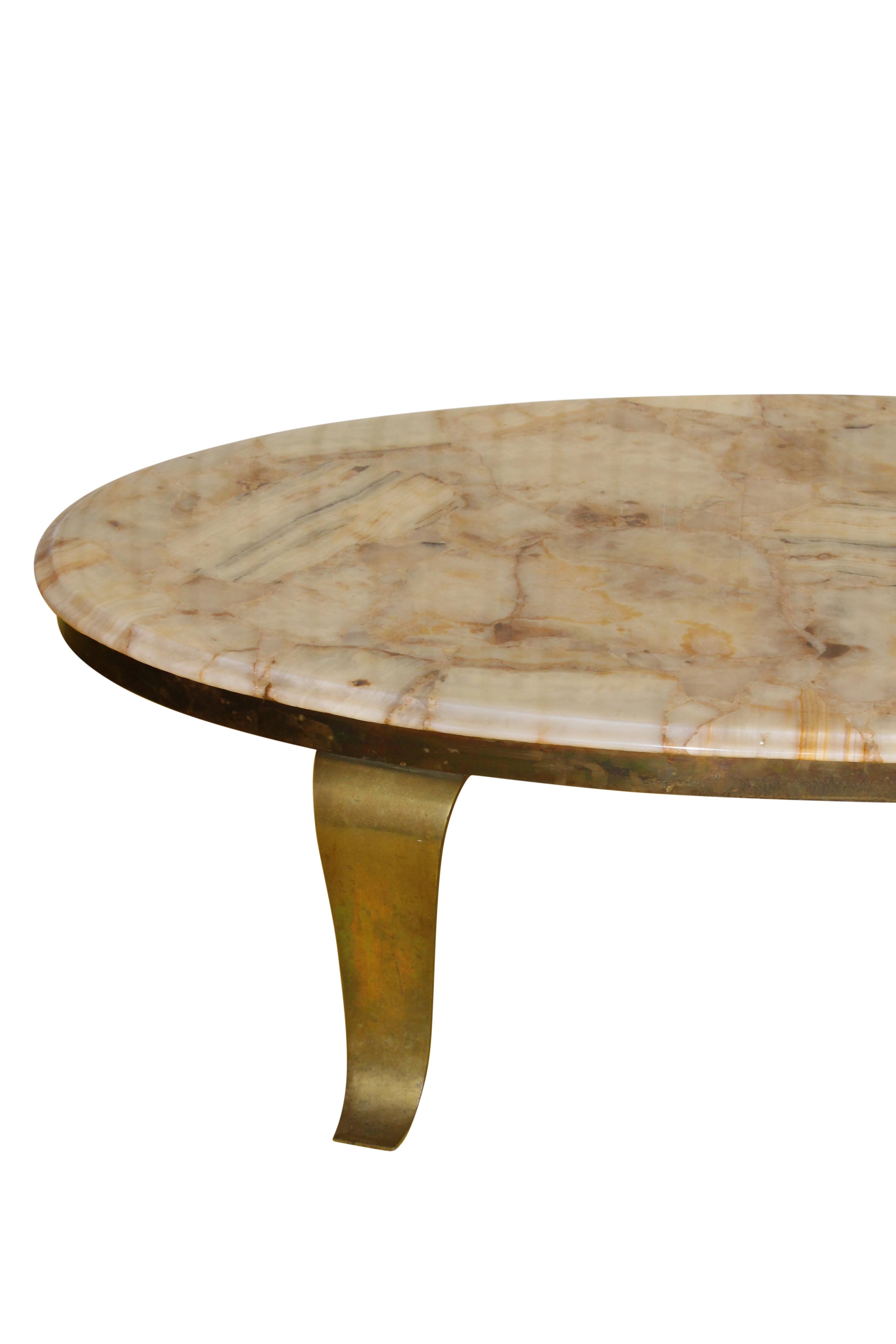 This Mid-Century Modern onyx and brass coffee table makes an elegant statement with its oval shape and delicately curved brass legs. Good condition for vintage status. The veining in the onyx is stunning and the colors emanates a soft glow.