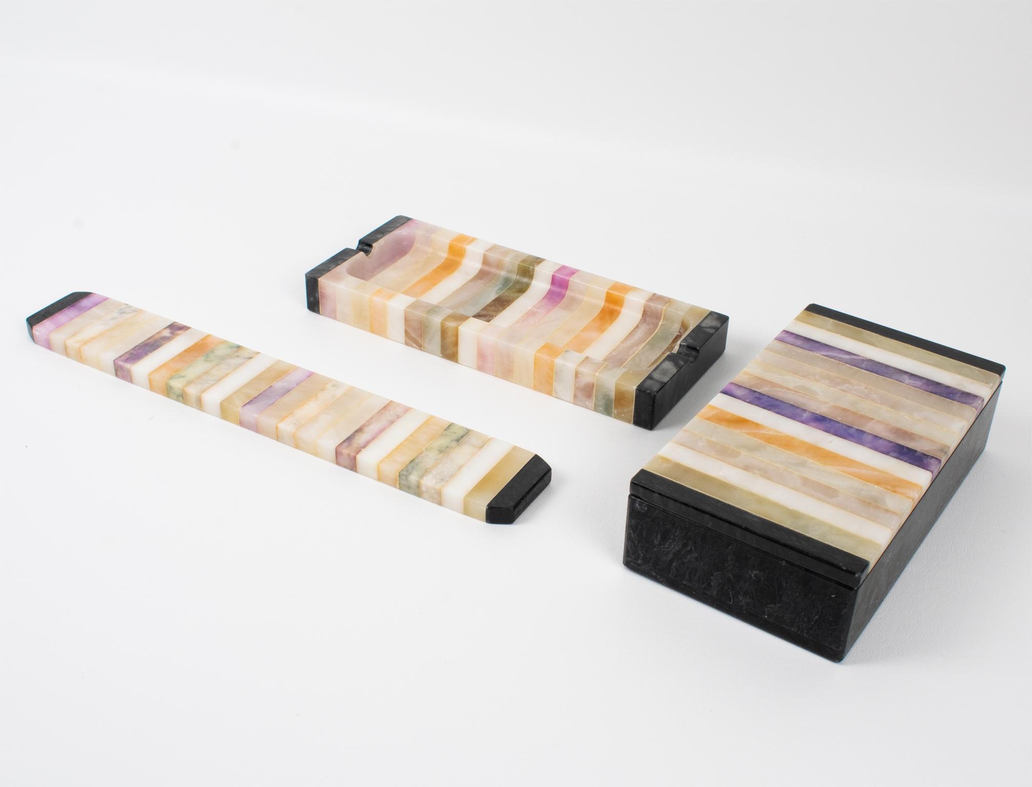 A rare functional Mid-Century modernist desk accessories set crafted in Italy in the 1960s. The set comprises three pieces: a pen holder, a box, and a ruler. The refined shape boasts marble and onyx stone geometric marquetry on each piece. This