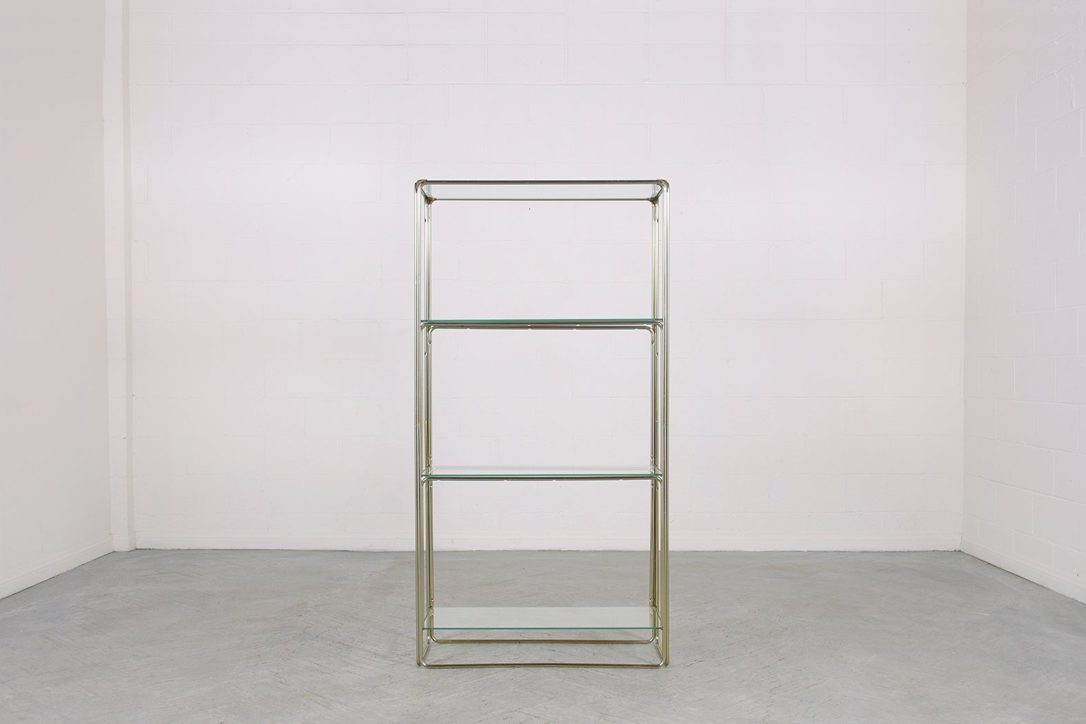 This extraordinary 1960s mid-century modern bookcase in good condition is beautifully hand-crafted out of clear glass and steel with a chrome finish. This vintage display clear glass open shelf features a sleek tubular chrome molding frame