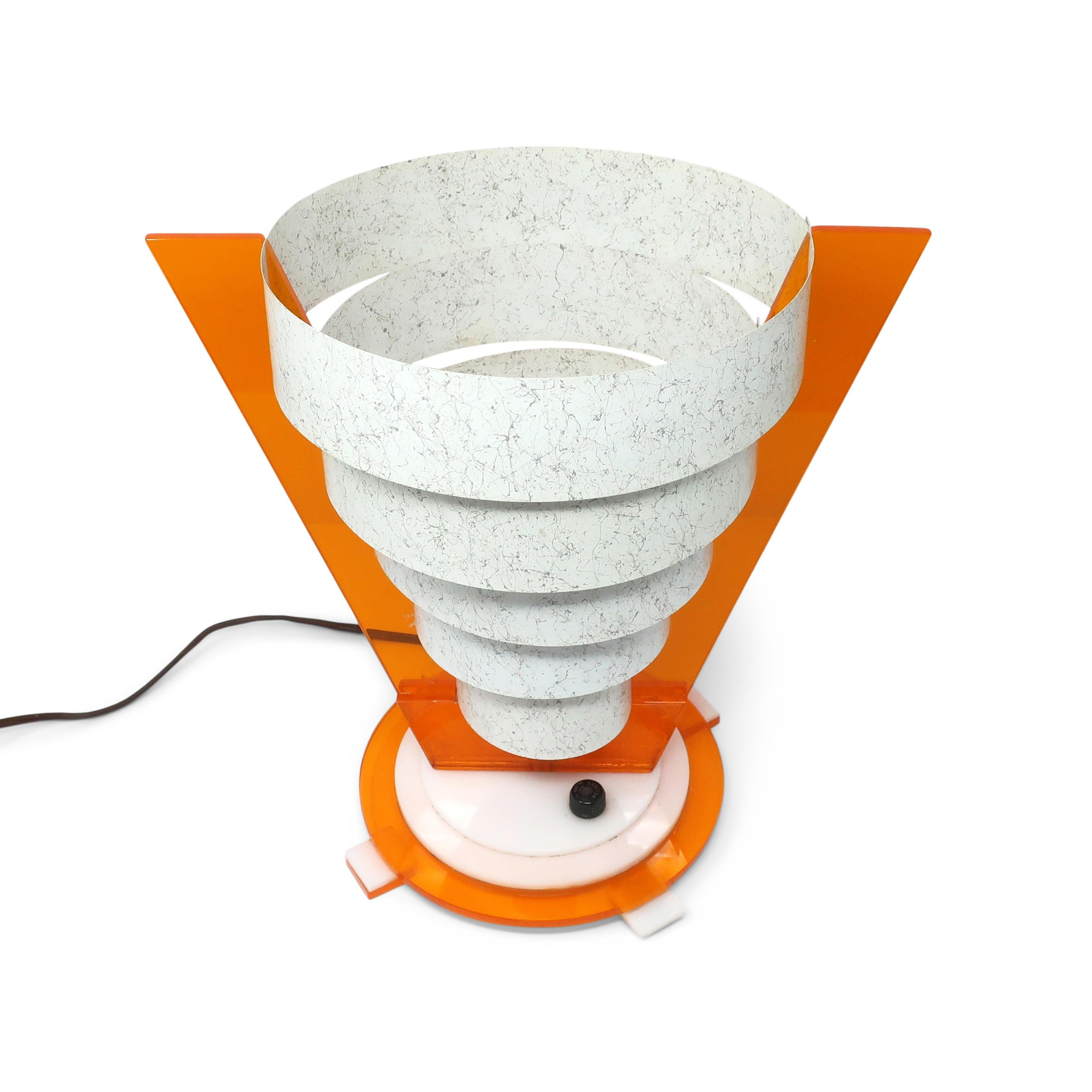 A fantastic mid-century table lamp that hits all the right atomic age, space age, and sputnik vibes!  Conical in shape with an orange and white lucite base, orange lucite upright supports, and gray splatter painted metal shade that bend to fit into