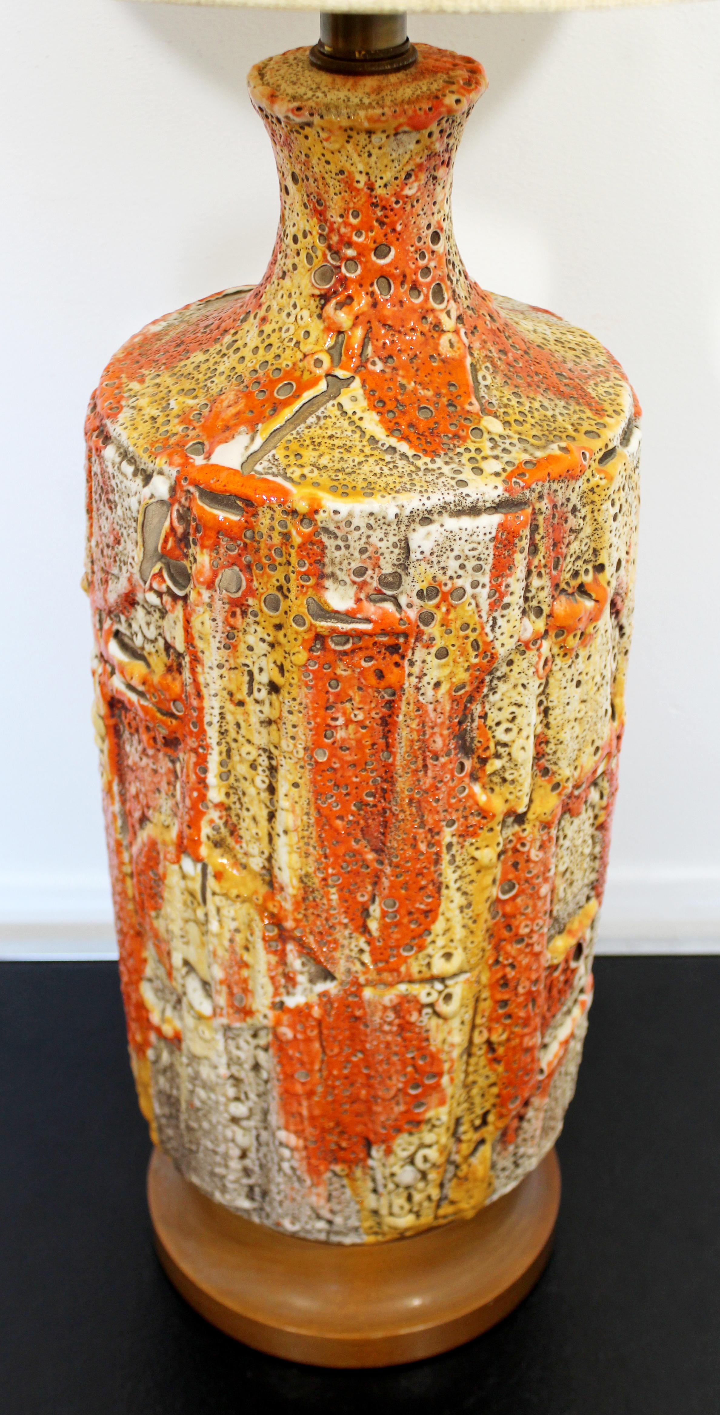 For your consideration is a organic looking, orange fat lava drip glazed ceramic table lamp, with original shade and cylindrical brass finial, circa 1960s. In excellent condition. The dimensions are 9