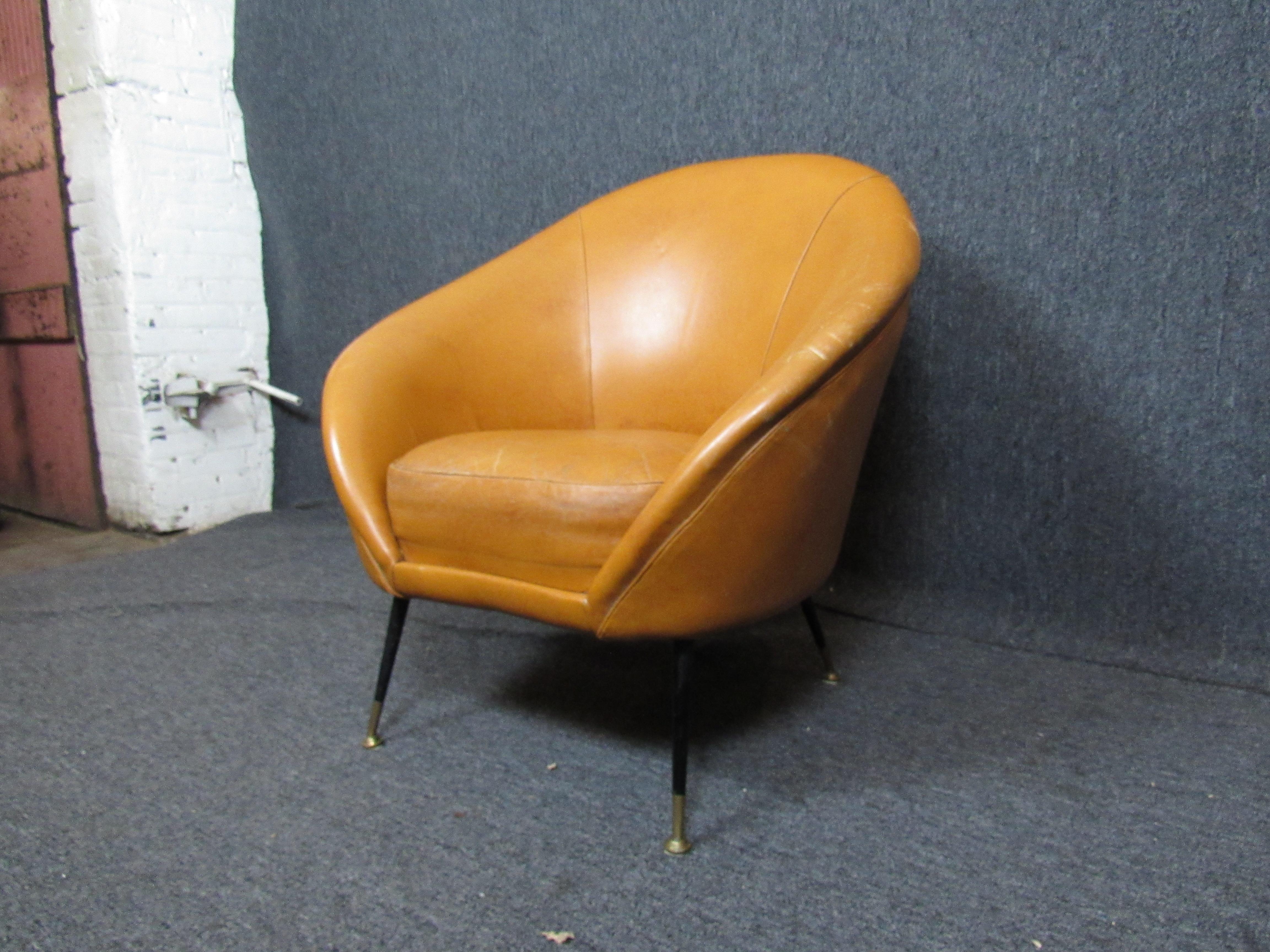 Wonderful orange leather club chair with a terrific vintage mod aesthetic! Broken-in orange leather seating provides plush comfort in style and brass leg accents are sure to add a touch of class to any room. 

(Please confirm item location - NY or