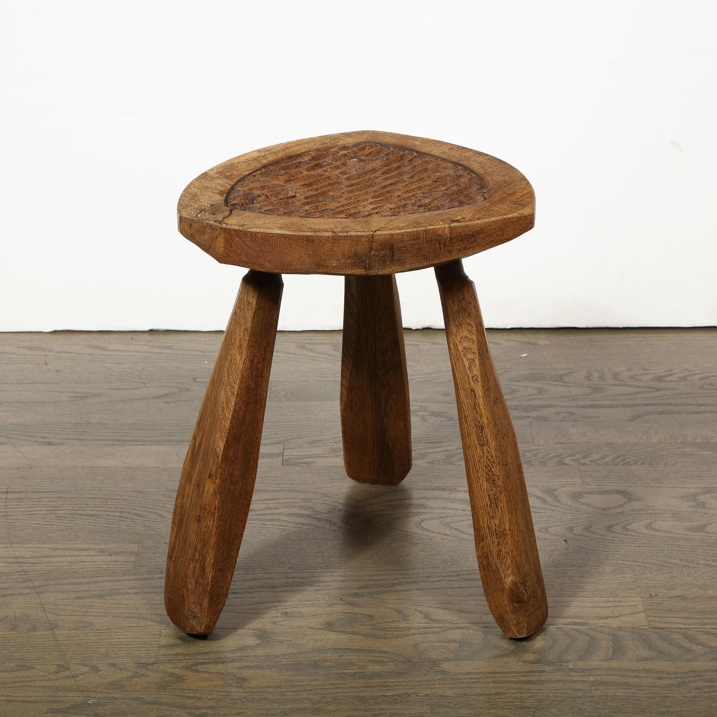 This refined and sophisticated Mid-Century Modern Brutalist stool was realized in France, circa 1950. It offers stylized shield form seats with rounded corners- a patently handcrafted form- with incised centres offering a wealth of carved ovoid