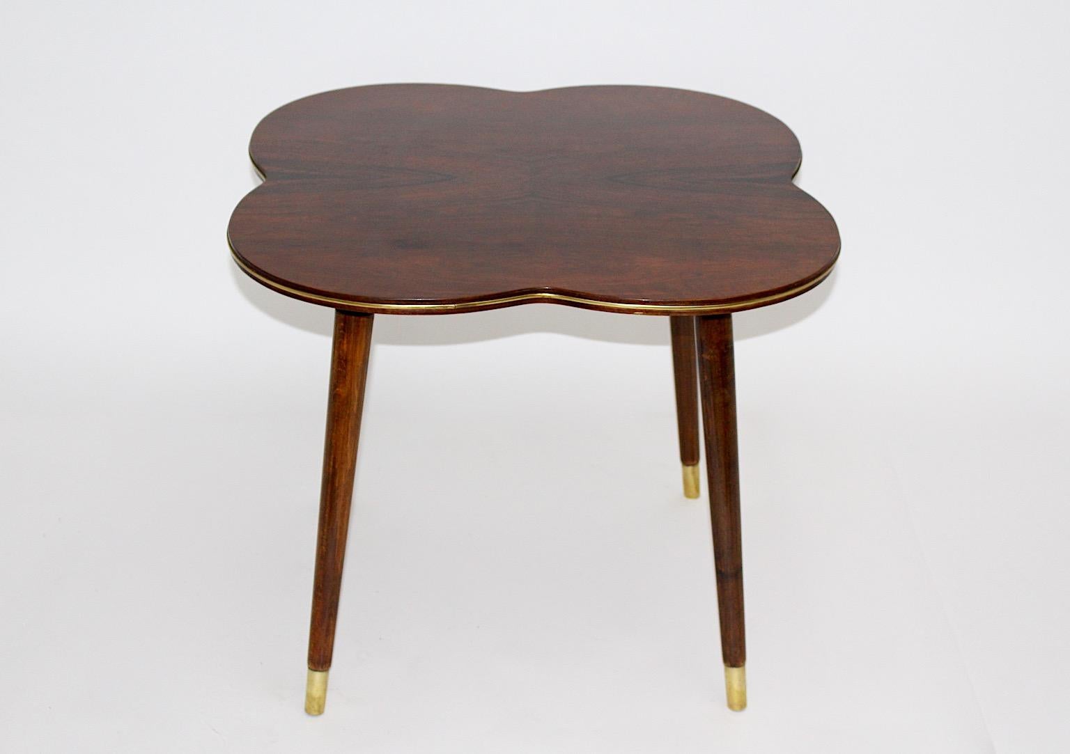 Mid Century Modern Vintage organischen Beistelltisch oder Couchtisch Kleeblatt wie aus Nussbaum und Messing circa 1950 Wien.
Ein charmanter Beistell- oder Couchtisch in Kleeblattform mit massiven Nussbaumbeinen und einer furnierten Platte, die eine