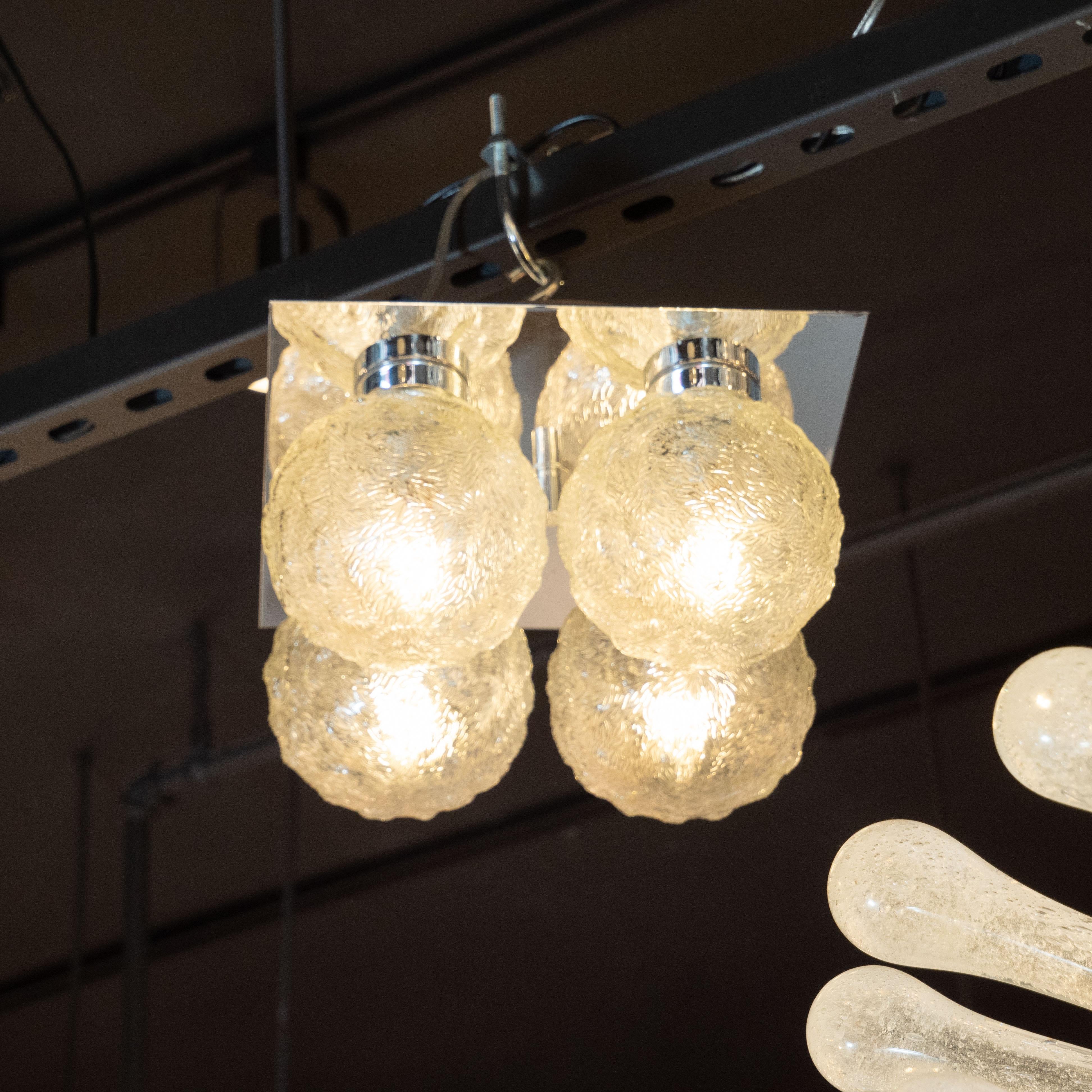 This elegant Mid-Century Modern flush mount chandelier was realized in Germany, circa 1960. It features four spherical shades in textured translucent glass- each with an abundance of organic curvilinear striations etched into the surface. The