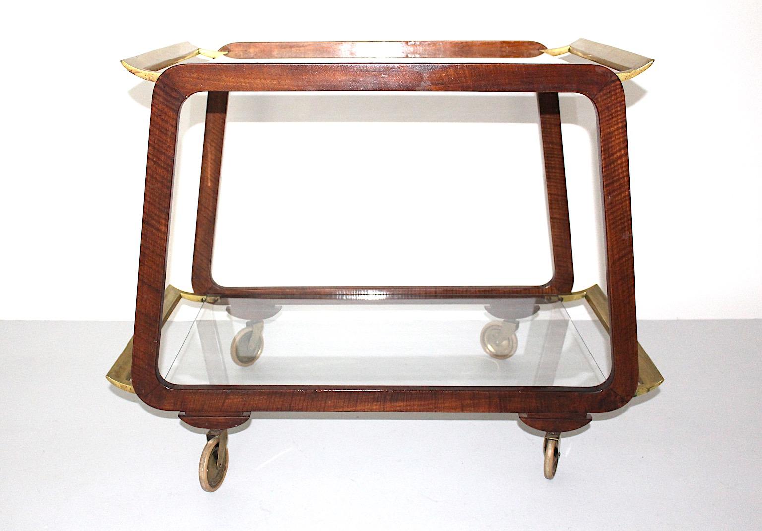 Chariot de service en noyer et laiton Vienne 1950s attribué à Oswald Haerdtl.
Un étonnant chariot de bar ou chariot de service vintage soutenu par des roues dans un ton de bois brun chaud de noyer avec des bords arrondis, du laiton et des verres