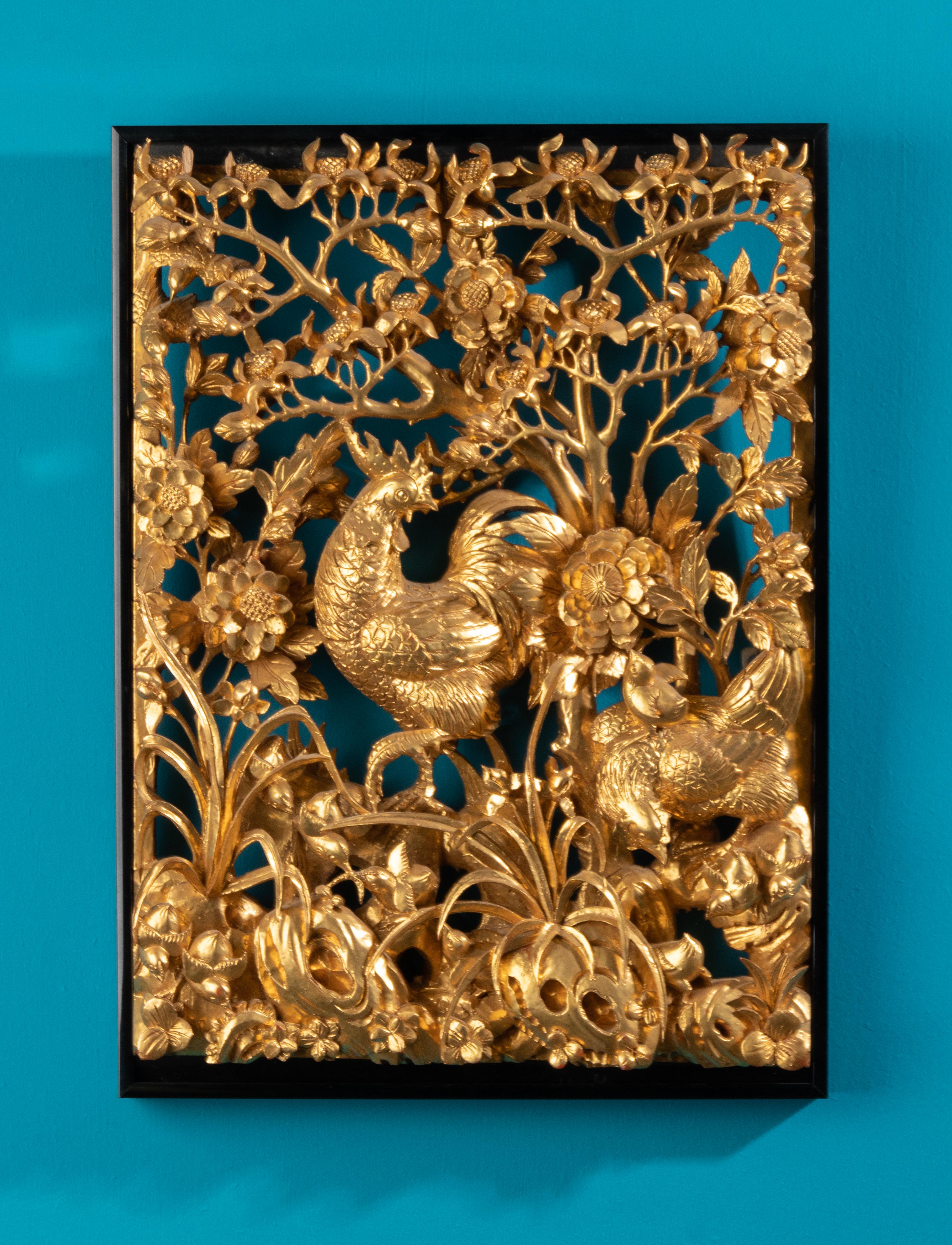 Bas-relief très détaillé de style chinois représentant un coq, des poulets, des fleurs de pivoine et un environnement floral. Il s'agit d'une sculpture murale de faible profondeur. Ce bas-relief rectangulaire est sculpté à la main dans du bois et