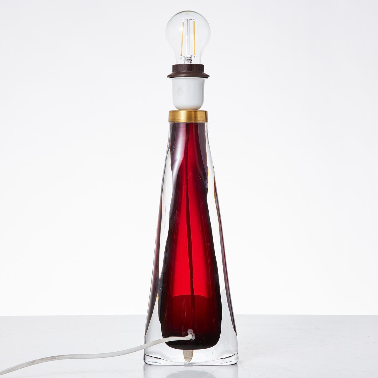 A striking mid-century modern table lamp designed by Carl Fagerlund for Orrefors, Sweden, circa 1960s. This sculptural lamp features a bold ruby red glass core encased in thick, clear crystal, showcasing Orrefors' signature quality and Fagerlund's