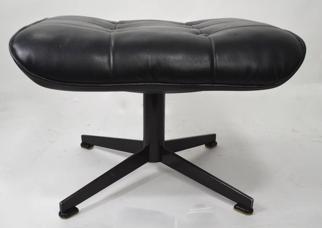 Black vinyl pad on iron grid structure, with iron base. This item can function as an ottoman, a footrest or a stool.