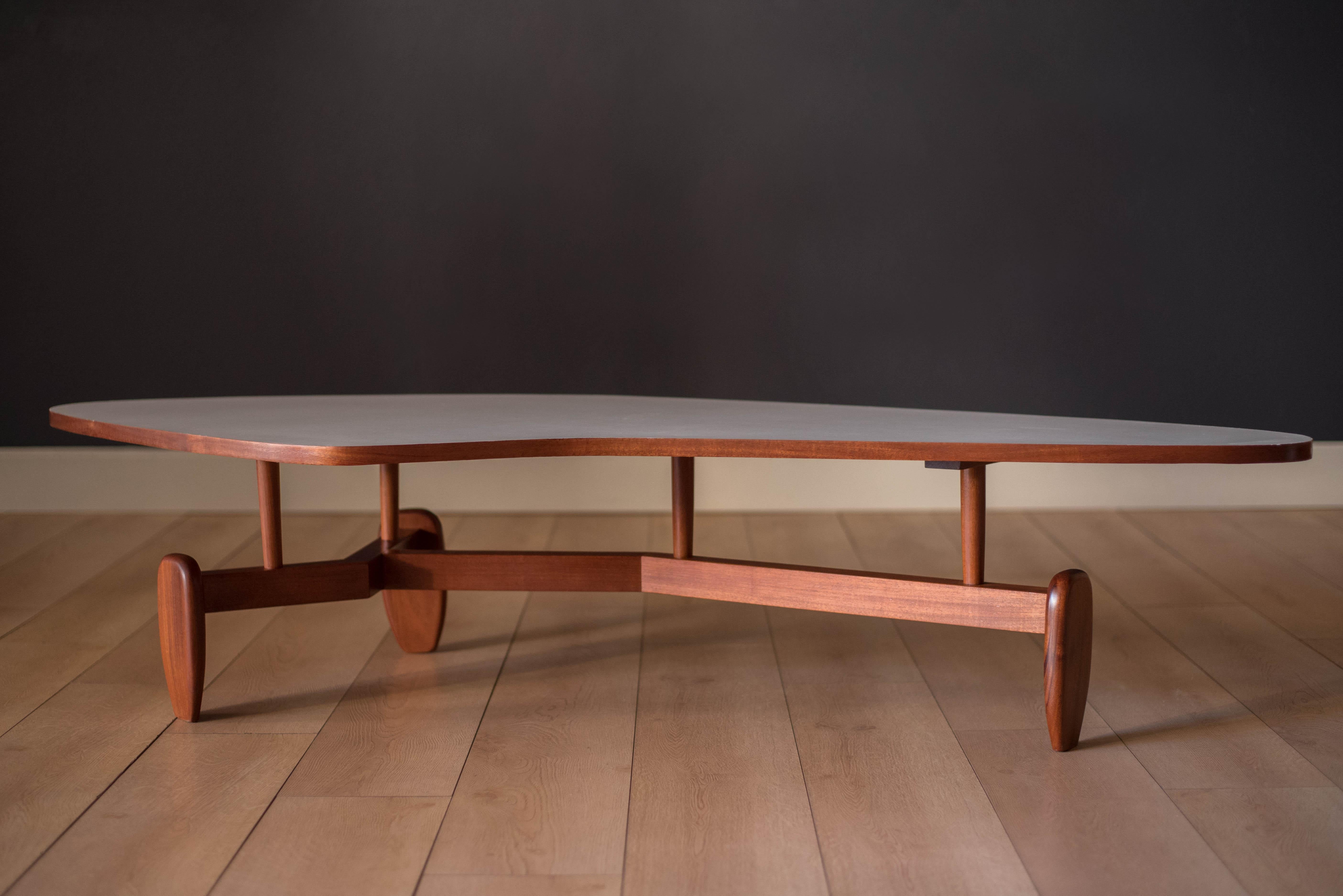 Vintage 'outrigger' coffee table designed by John Keal for Brown Saltman of California, circa 1950s. This conversation piece has a easy to maintain white laminate boomerang top with contrasting mahogany trim. Structural solid mahogany floating base