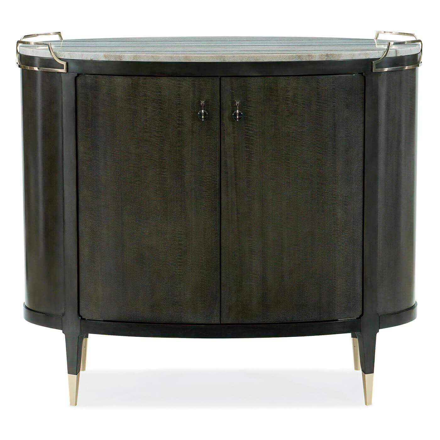 A Mid-Century Modern-Style oval bar cabinet with a striking sandstone top. The elegant top is trimmed with crisscrossing gold finish handles. This beautiful piece is finished all around and has two curved doors with custom metal pulls. The inside