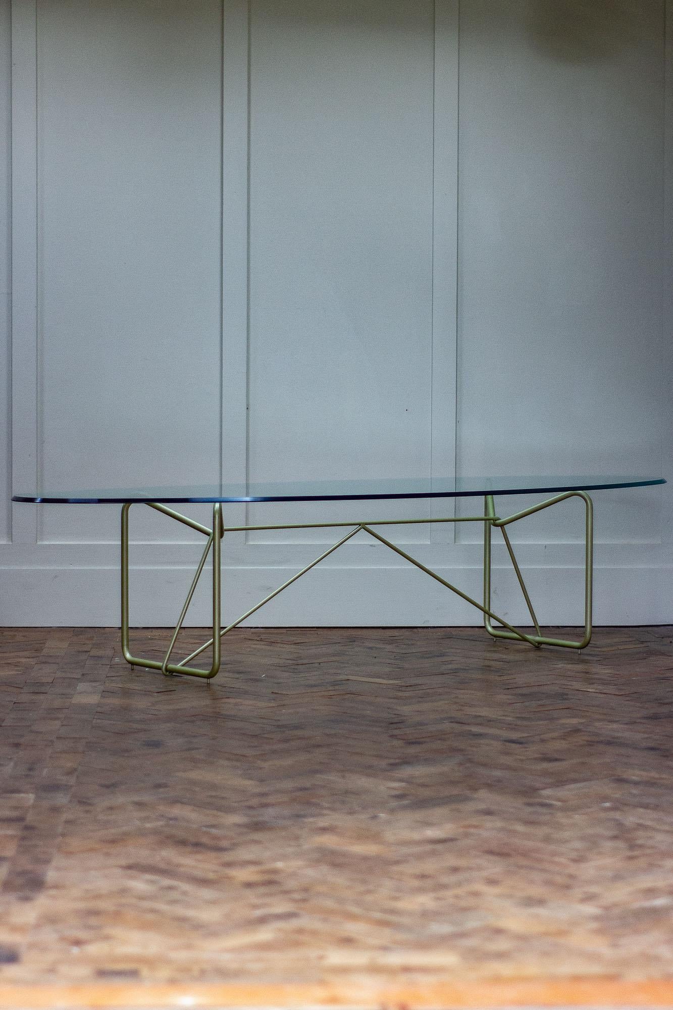 Oval glass top coffee table with a tubular metal frame base. The glass has a bevelled edge to it which can be placed any way up. 

The base which is painted has an interesting design and is in great condition.

The glass has had a small repair