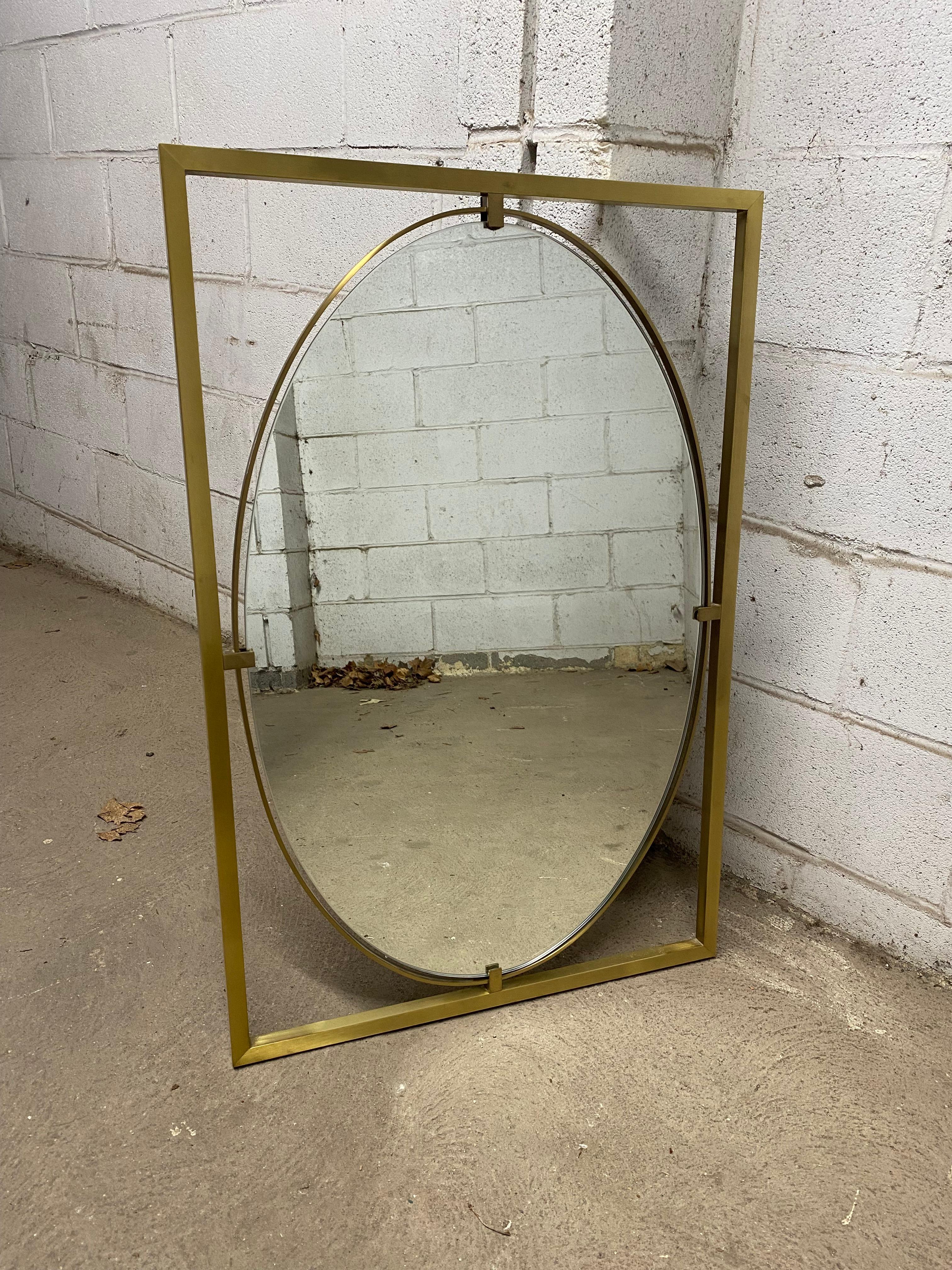 Rectangular square stock brass finished brushed aluminum frame. The frame surrounds a beveled edge oval mirror. Circa 1960-65. Good overall condition. No visible chips or dings to the glass. The aluminum frame is in good condition with minor wear