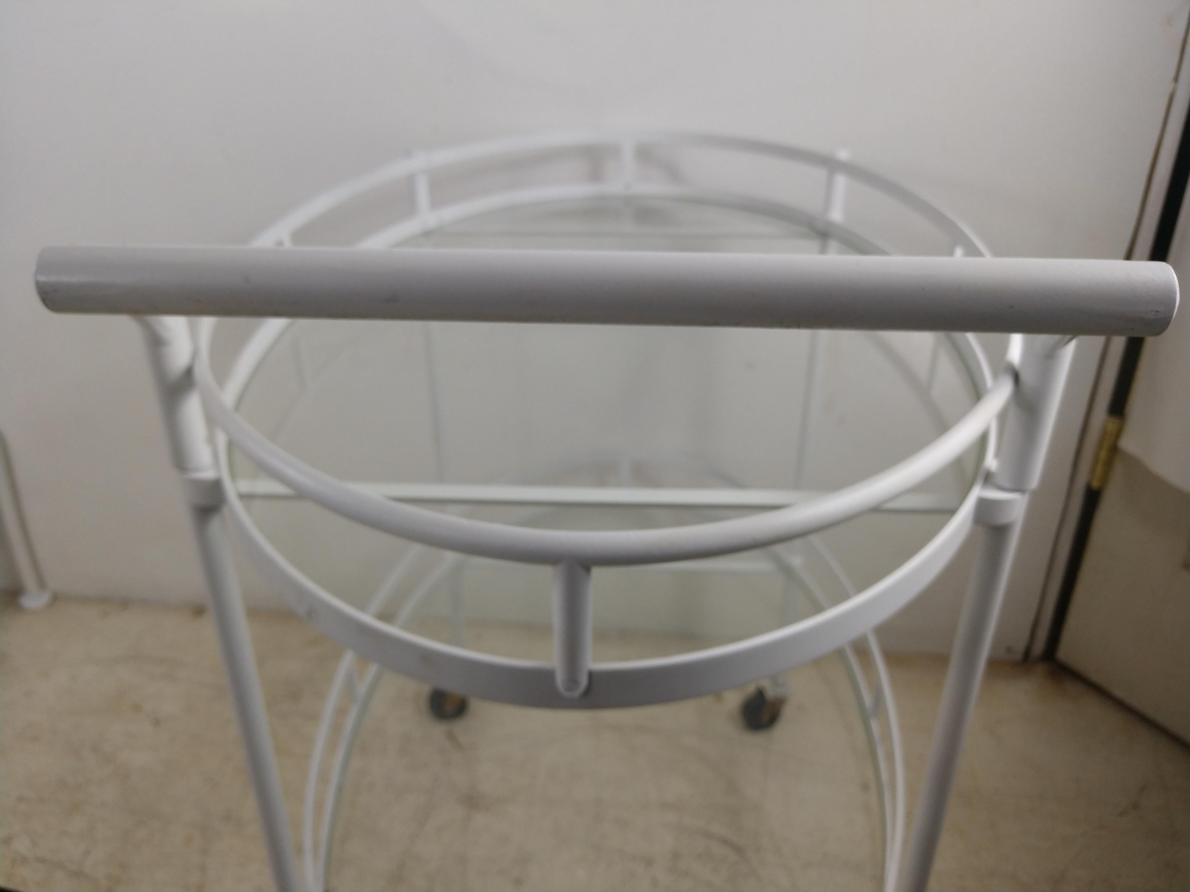 Brass bar cart painted enamel white. Two oval tiers with glass shelves to house your beverages and glassware. Hard plastic wheels which operate freely.